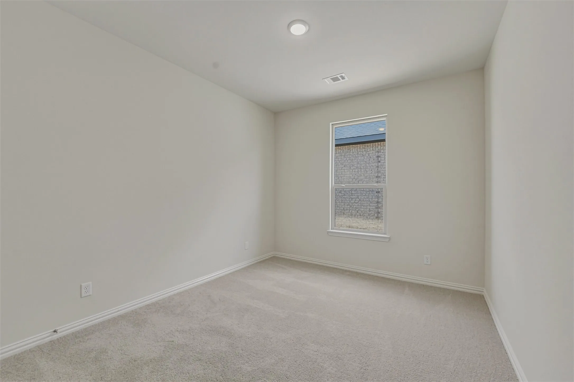 Neutral wall paint, light gray carpeting, recessed ceiling light, white trim, and a window with a white frame