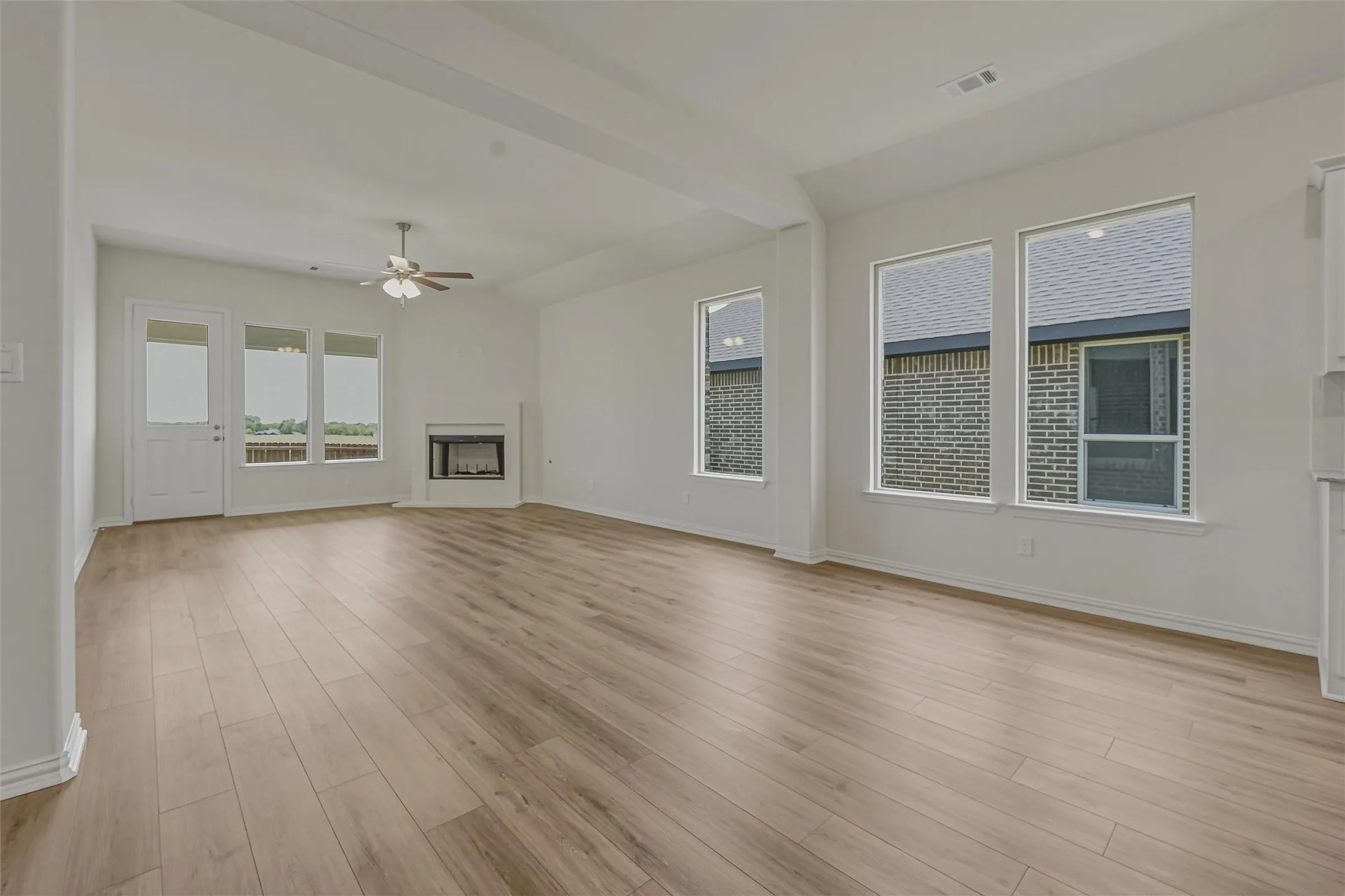 Spacious living area featuring wood-finish flooring, a ceiling fan, a built-in fireplace, and expansive windows