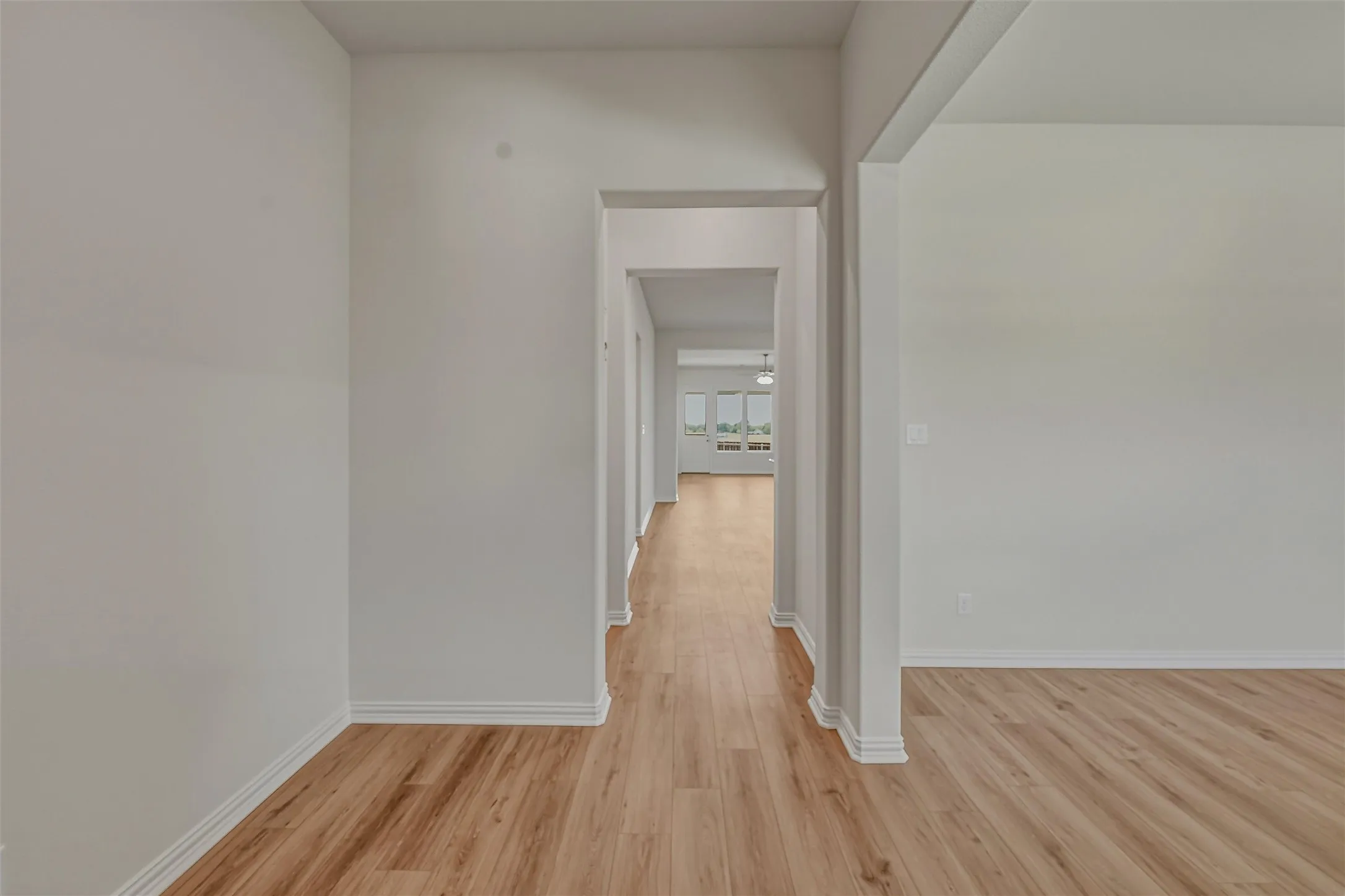 Hallway featuring wood-finish flooring, white baseboards, and neutral wall paint