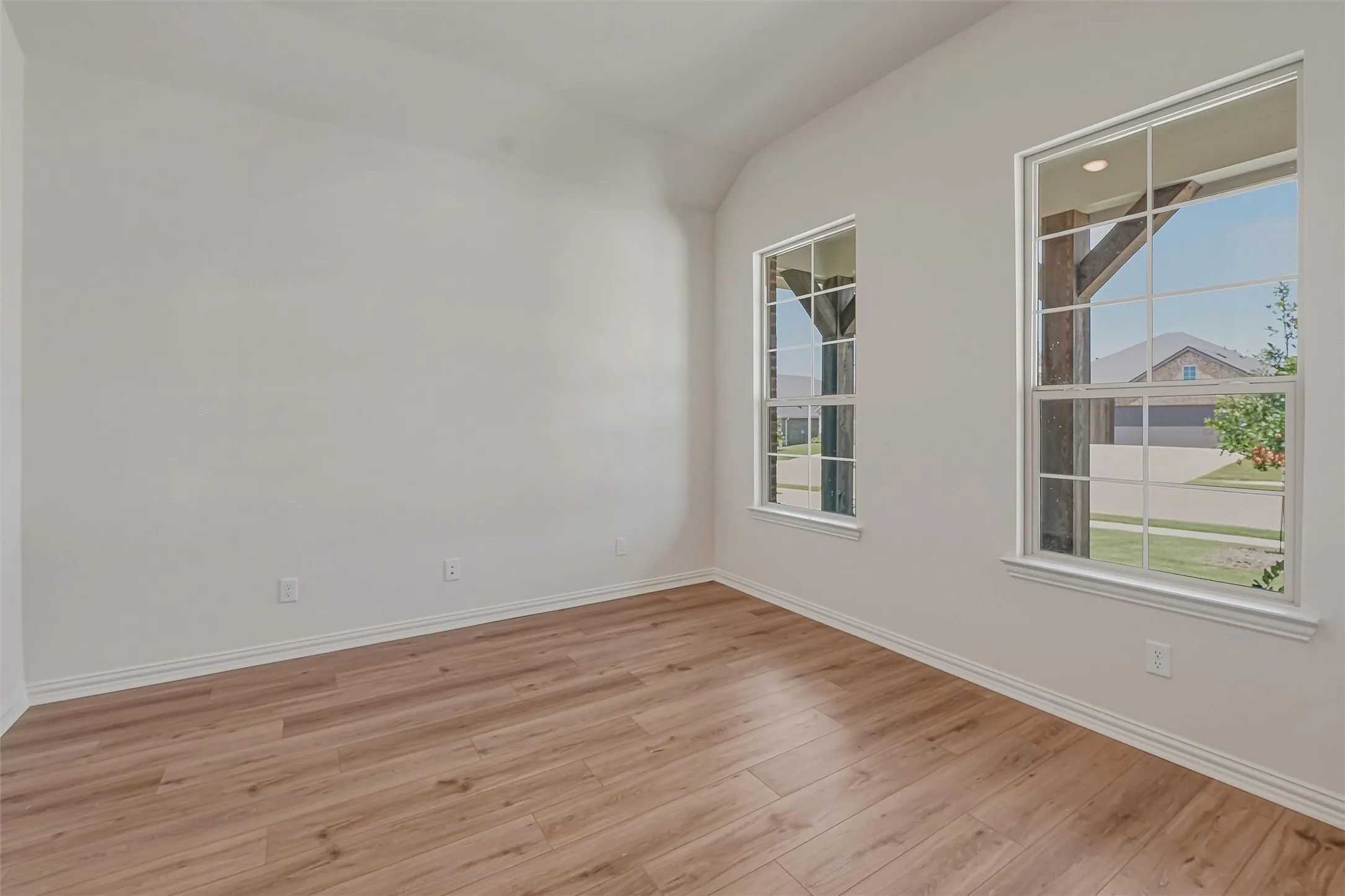 Interior space featuring wood-finish flooring, crisp white walls, and bright window frames