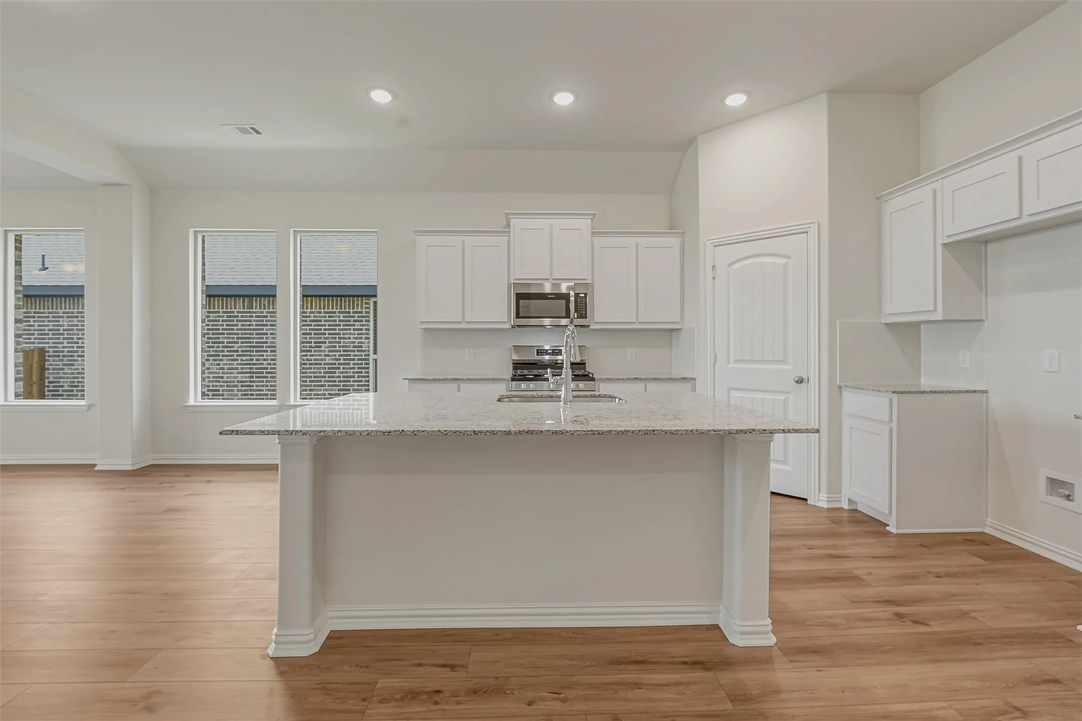 Modern kitchen island featuring a light-toned countertop, integrated sink, and stainless steel faucet