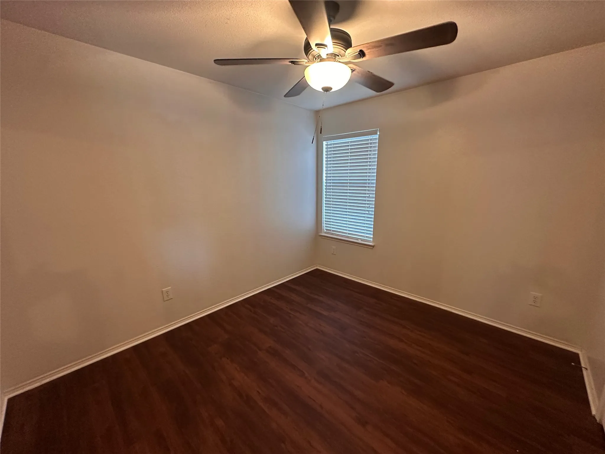 Wood-finish flooring, single window with blinds, ceiling fan with integrated lighting