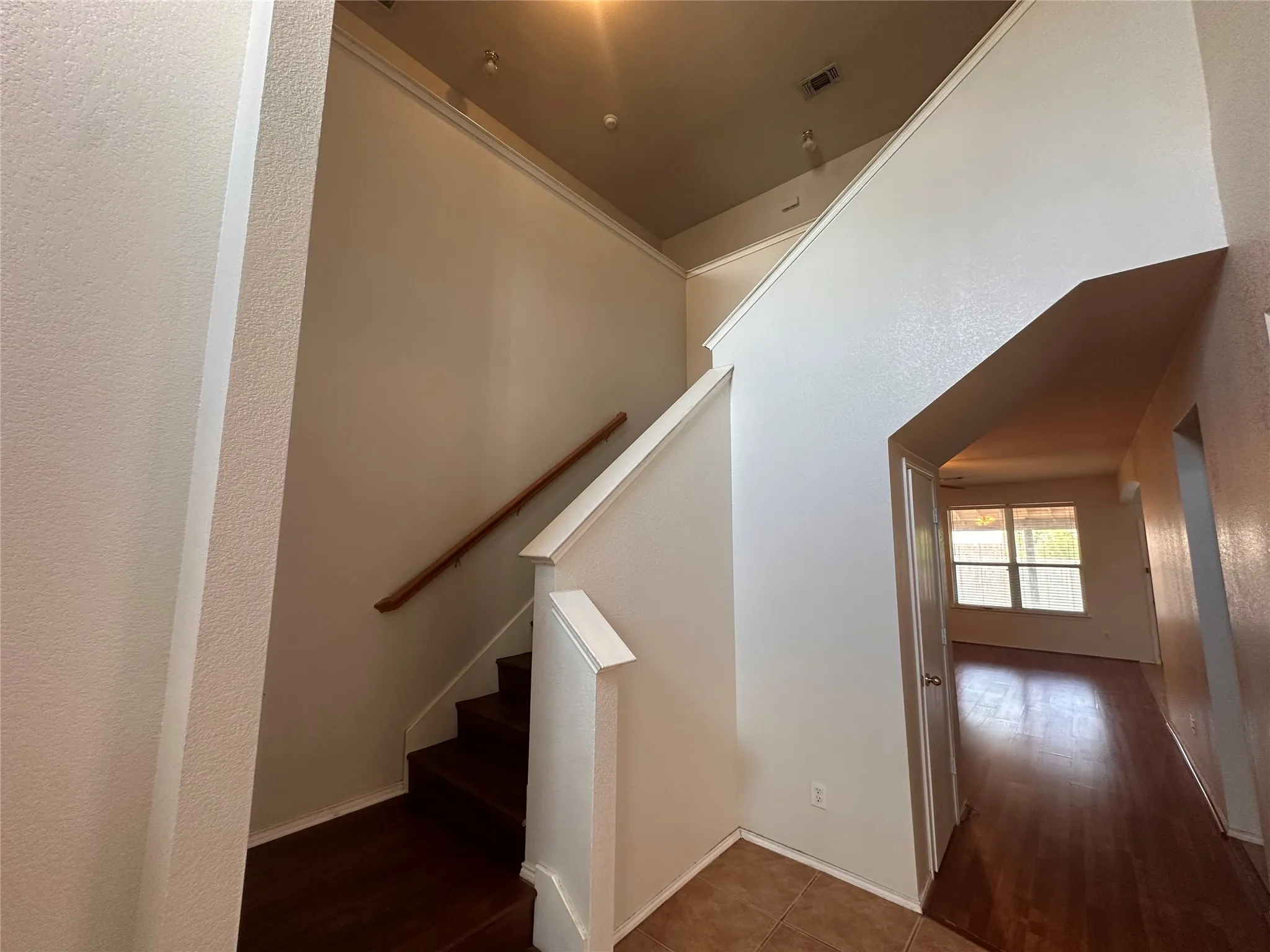 Two-story entry featuring wood-finish staircase with white risers and handrail, recessed lighting, and tile flooring