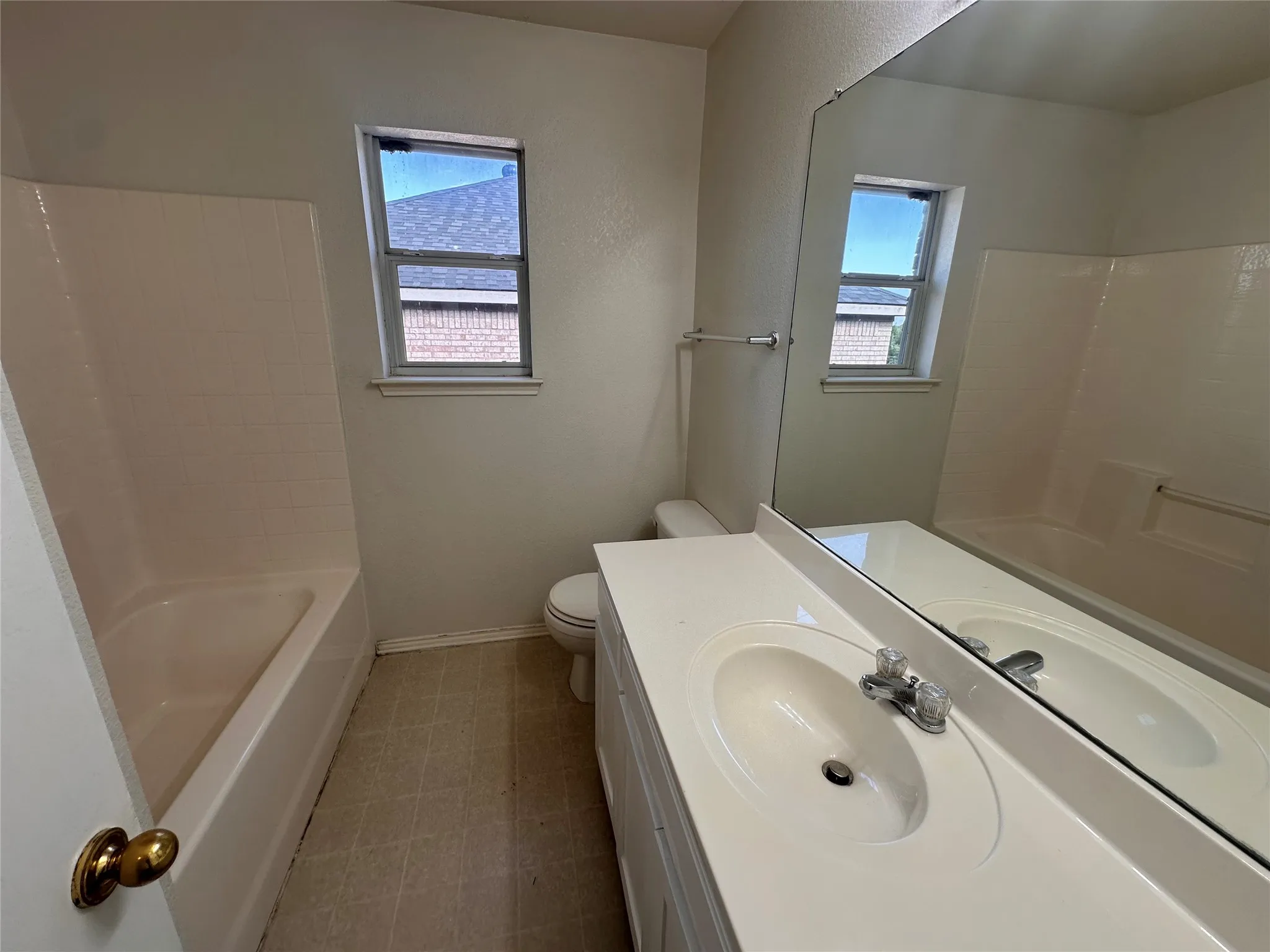 Integrated vanity with a single basin sink, wall-mounted mirror, and a bathtub with a shower surround