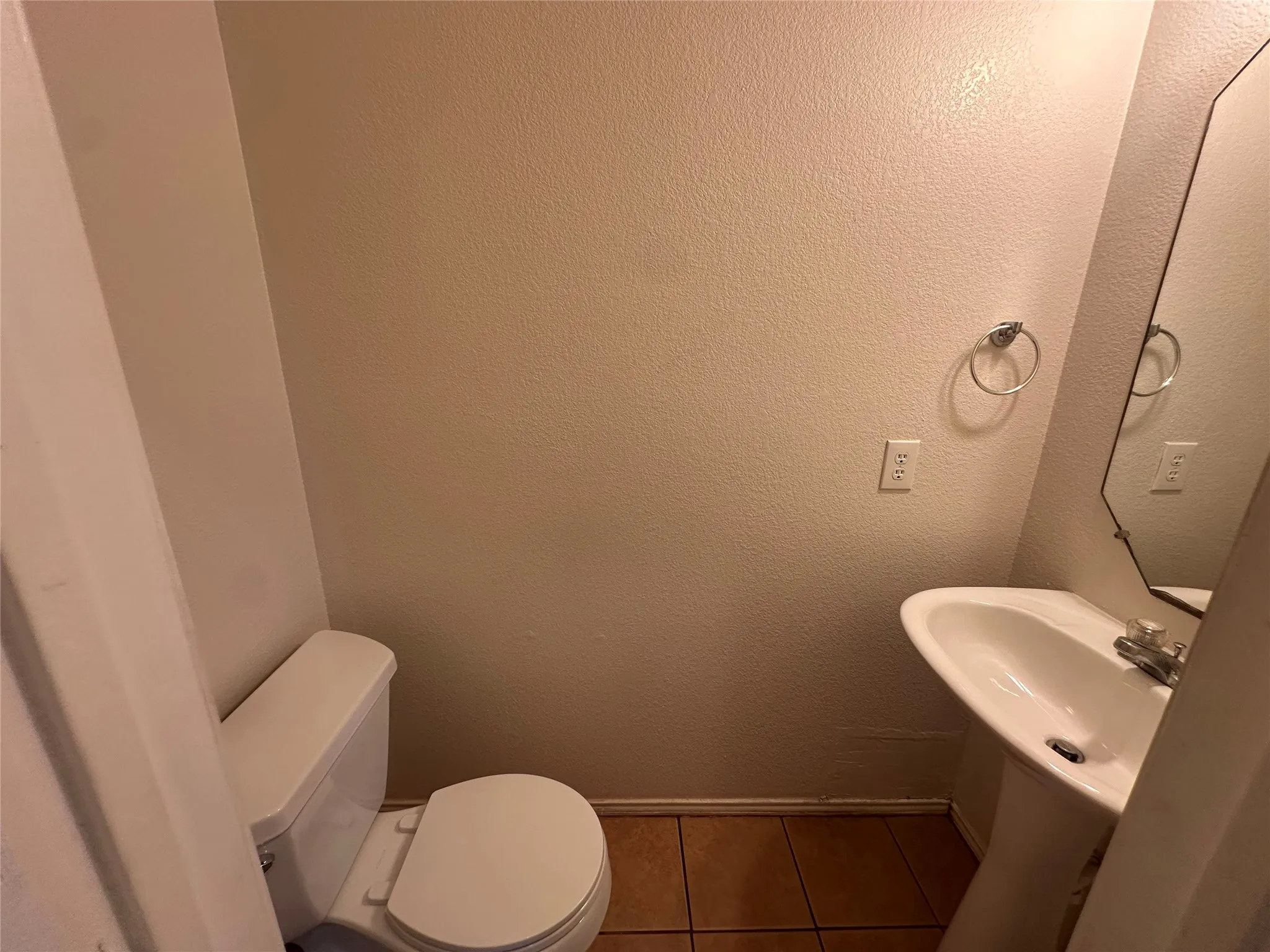 White pedestal sink with chrome faucet, mounted mirror, and a white toilet