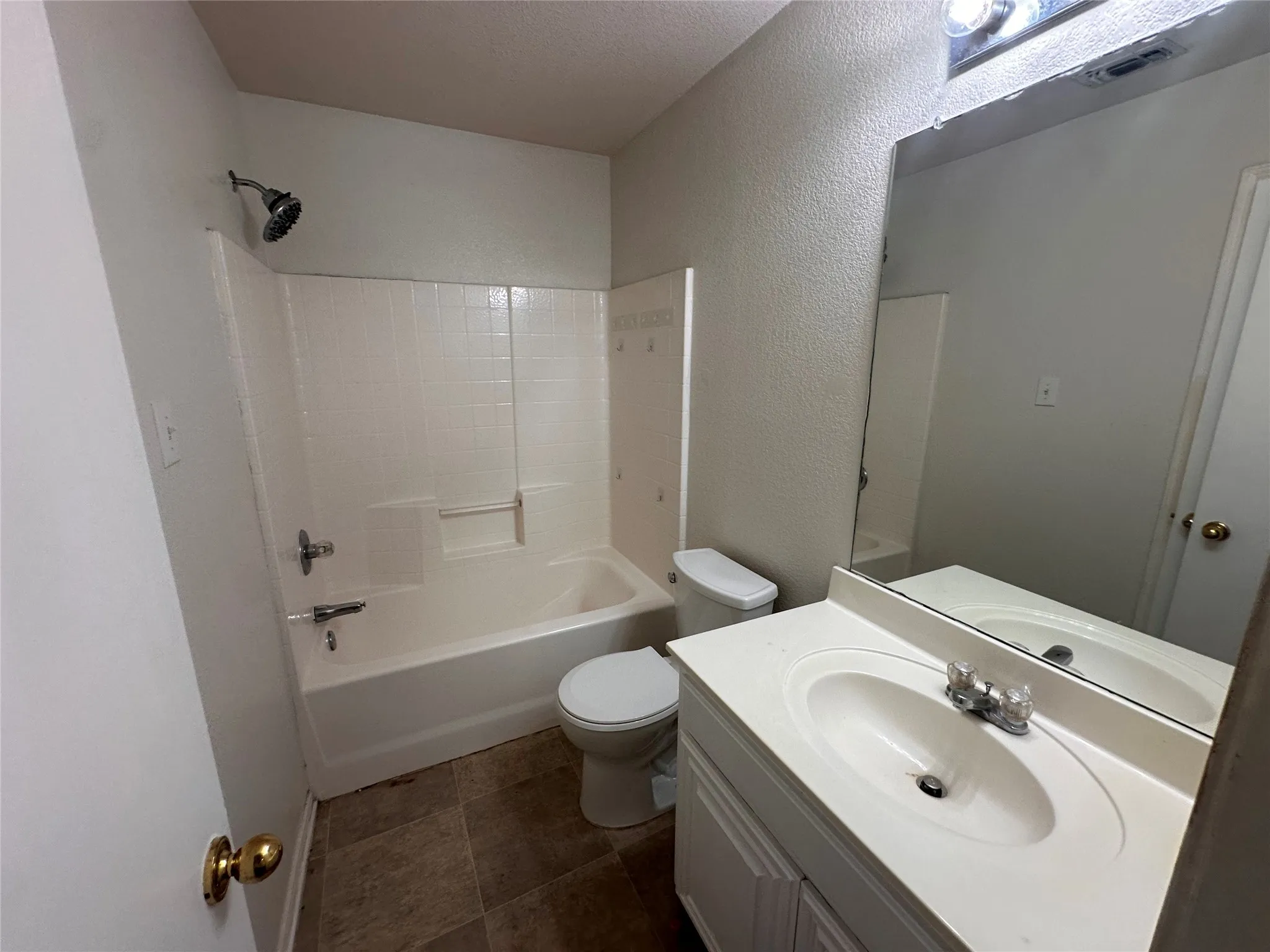 Bathroom featuring a combined shower and tub, tile flooring, a single vanity with an integrated sink, and an unframed mirror