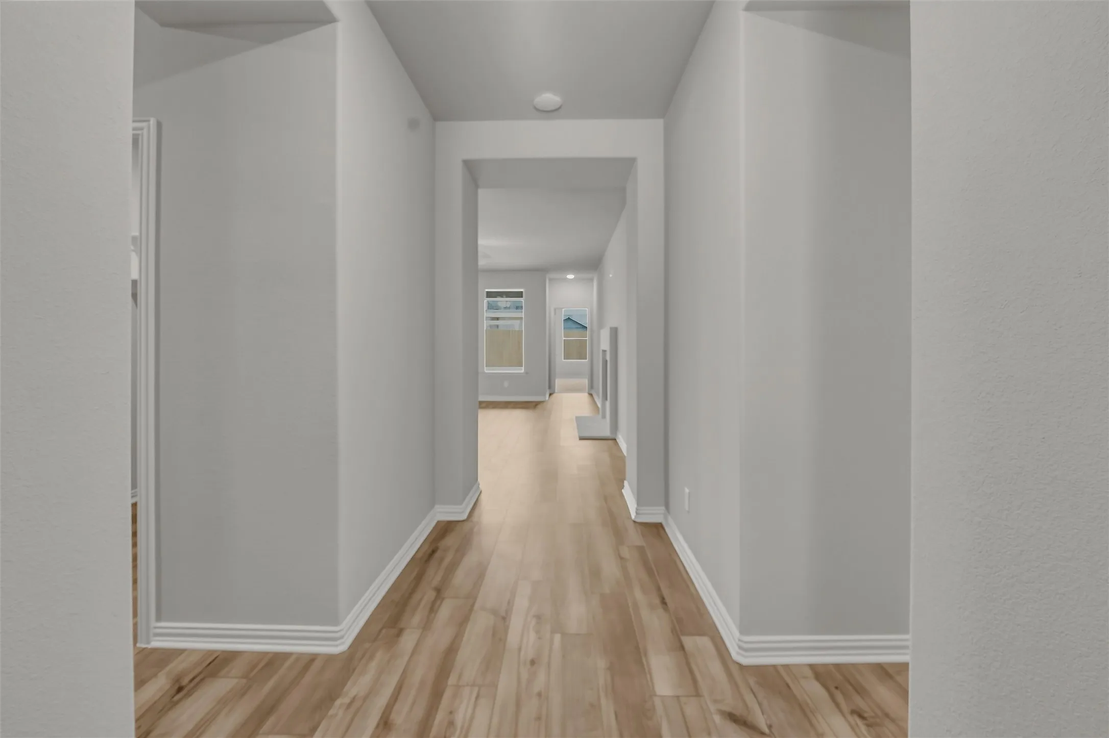 Hallway with wood-finish flooring, white baseboards, and light gray wall paint