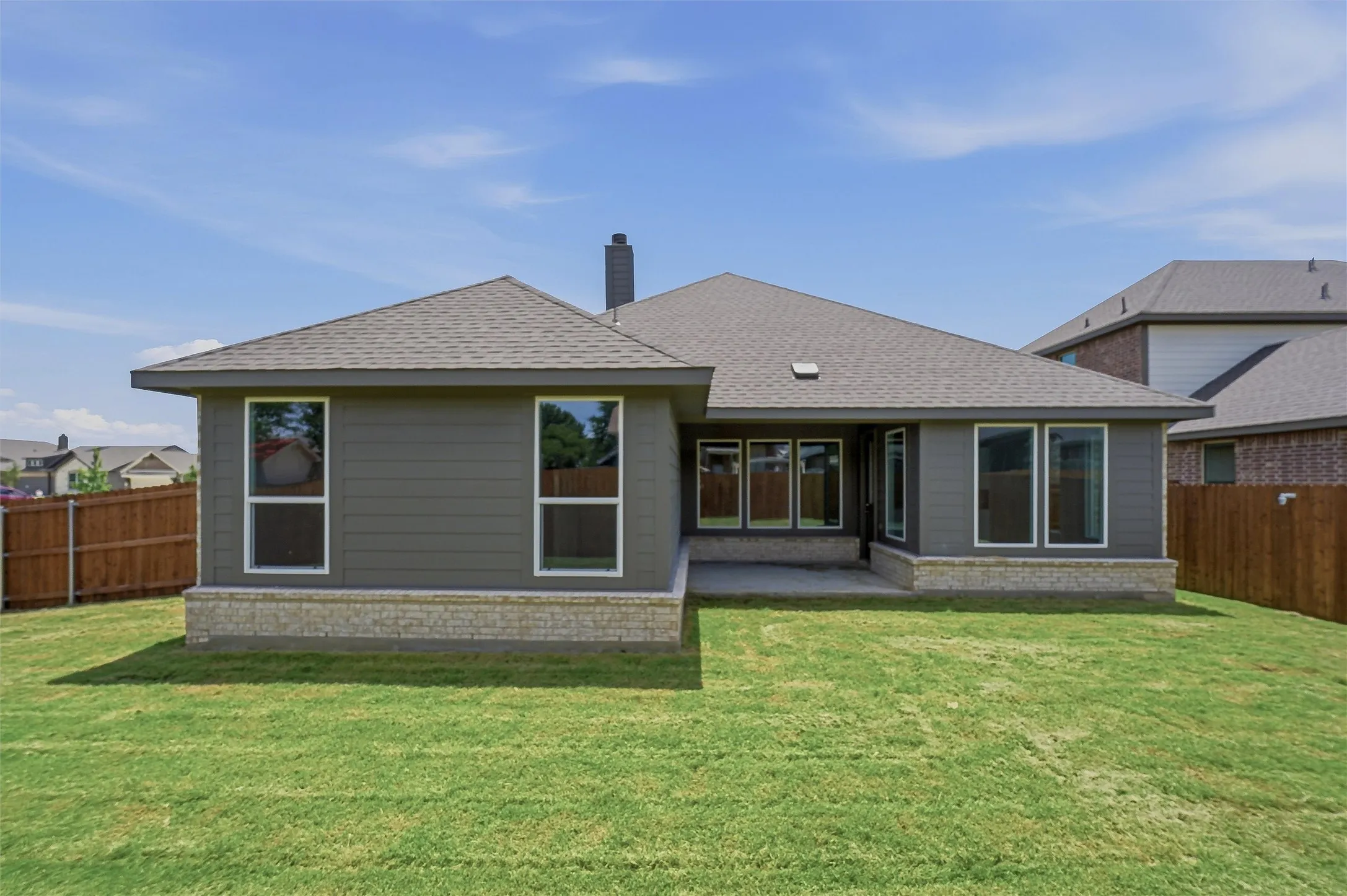 Rear exterior featuring a stone foundation, horizontal siding, a covered patio, and a shingle roof
