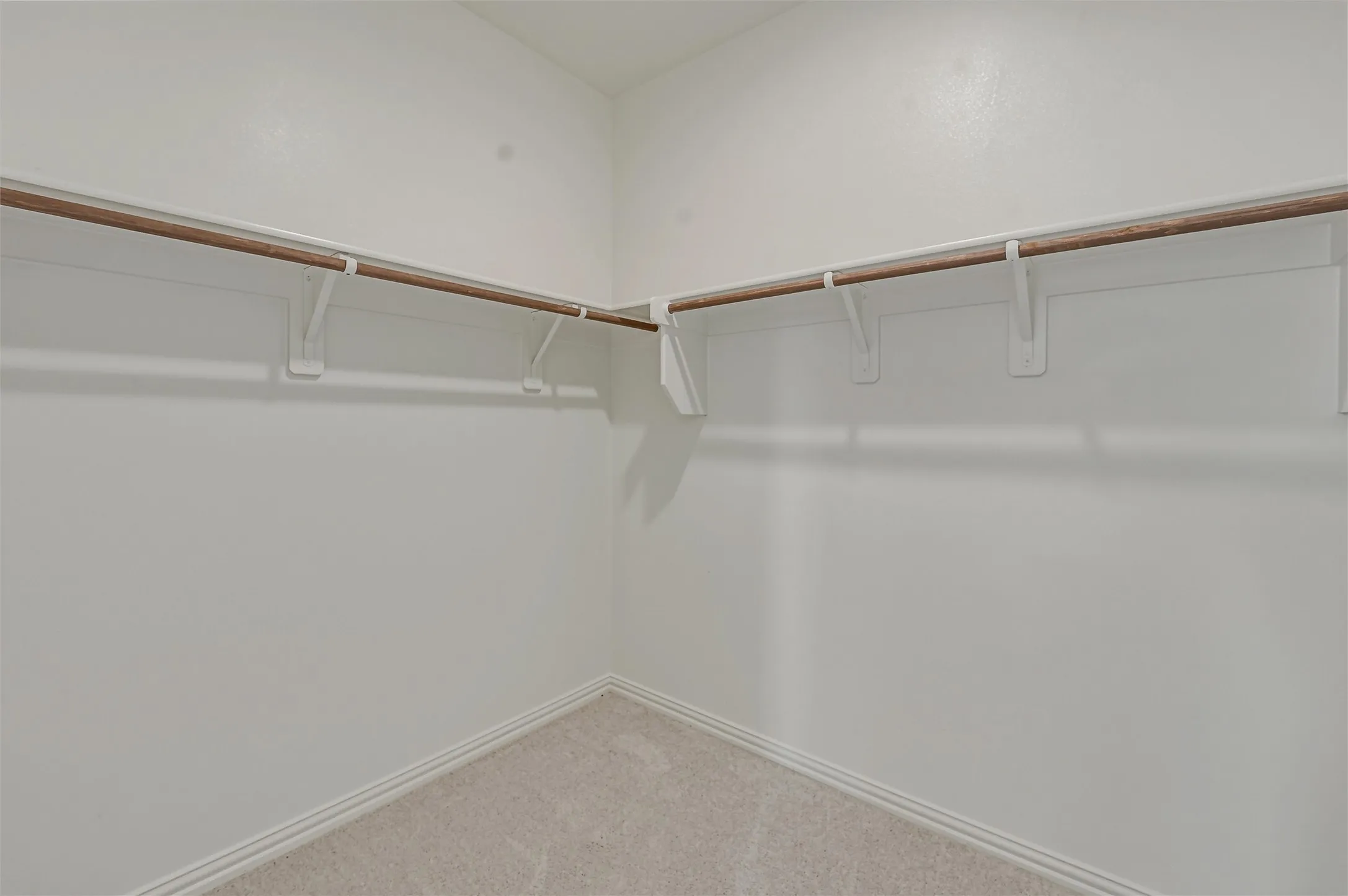 Corner closet featuring white walls, baseboards, and neutral-toned carpet flooring