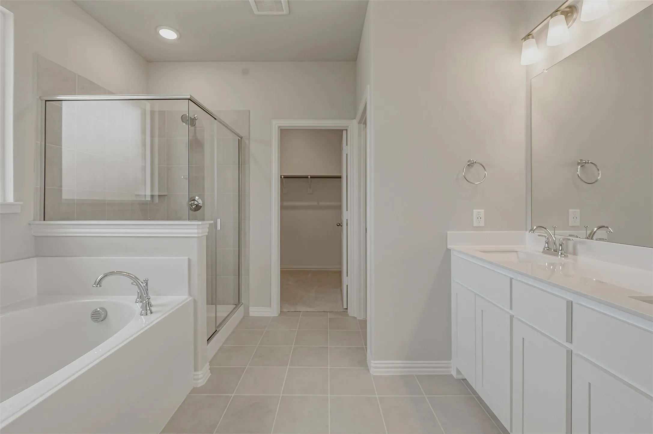 Bathroom featuring a built-in tub, separate glass-enclosed shower, dual vanity with undermount sinks, chrome fixtures, and tiled flooring