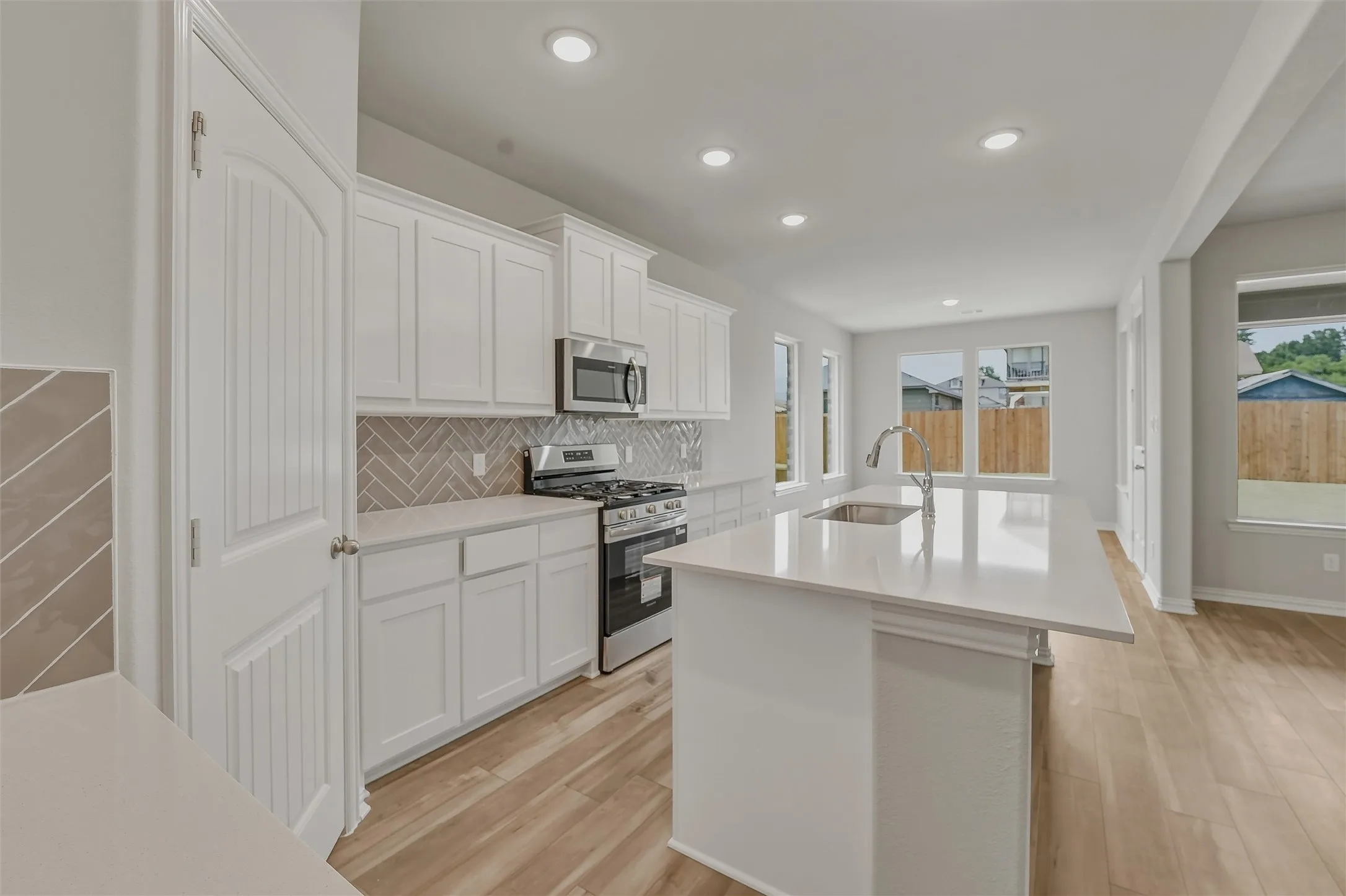 Modern kitchen featuring a large central island with an undermount sink and gooseneck faucet