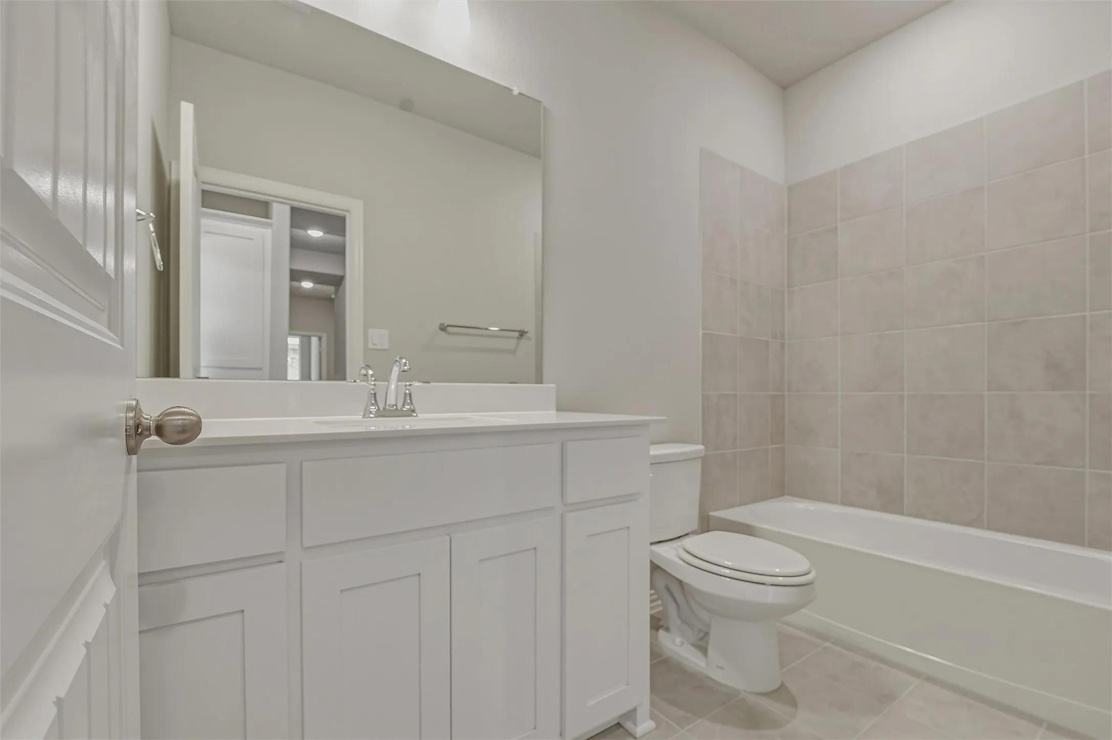 Bathroom featuring a white vanity with an integrated sink, chrome faucet, and expansive wall mirror