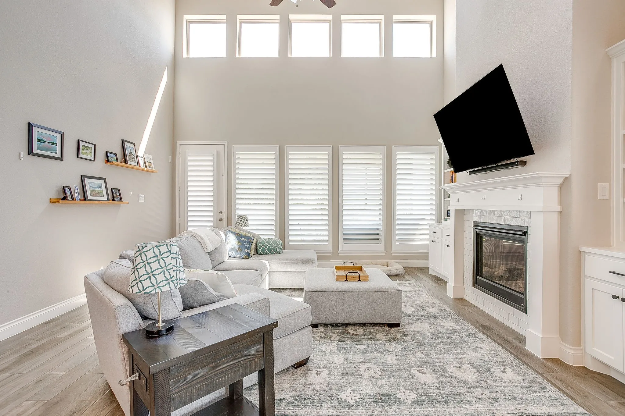 The spacious living area features soaring ceilings, a gorgeous fireplace surrounded by beautiful built-ins, and stunning walls of windows that flood the space with natural light.
