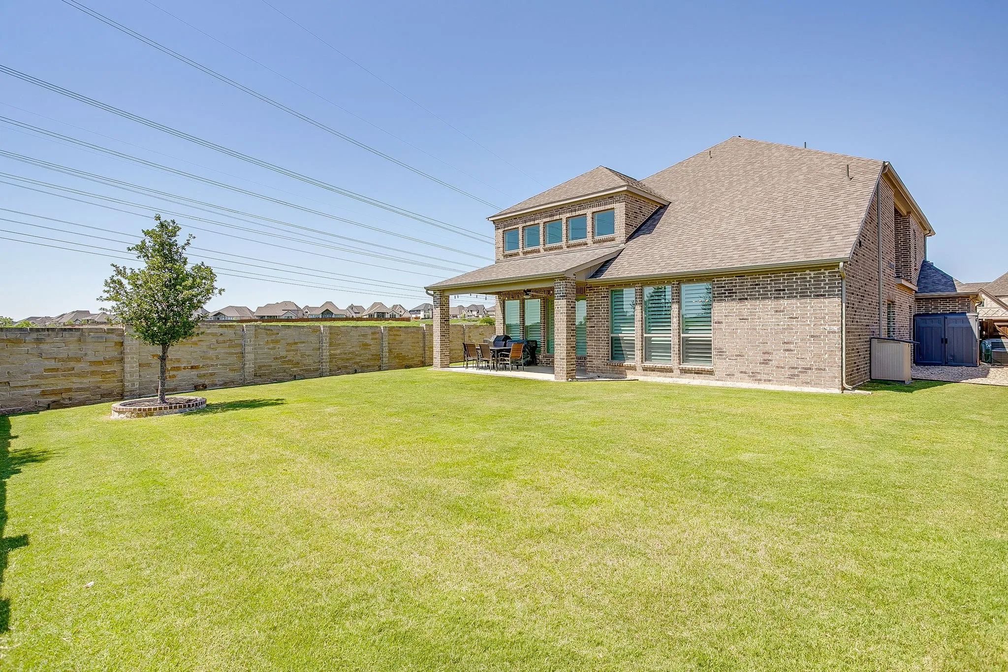 Spacious backyard featuring a manicured lawn and a beautiful brick privacy wall!
