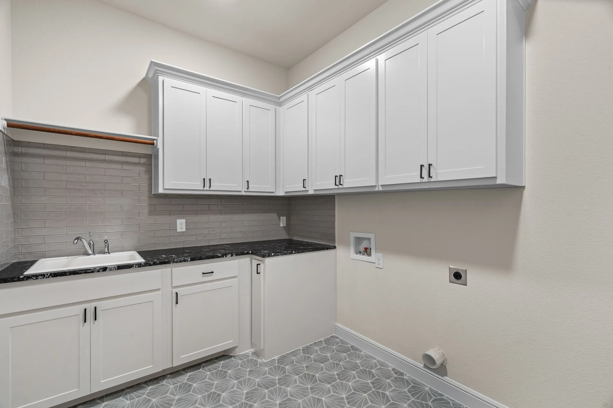 Laundry Room is Complete with Concrete Tile Floors, Abundant Cabinetry, Sink & Extra Fridge or Freezer Space