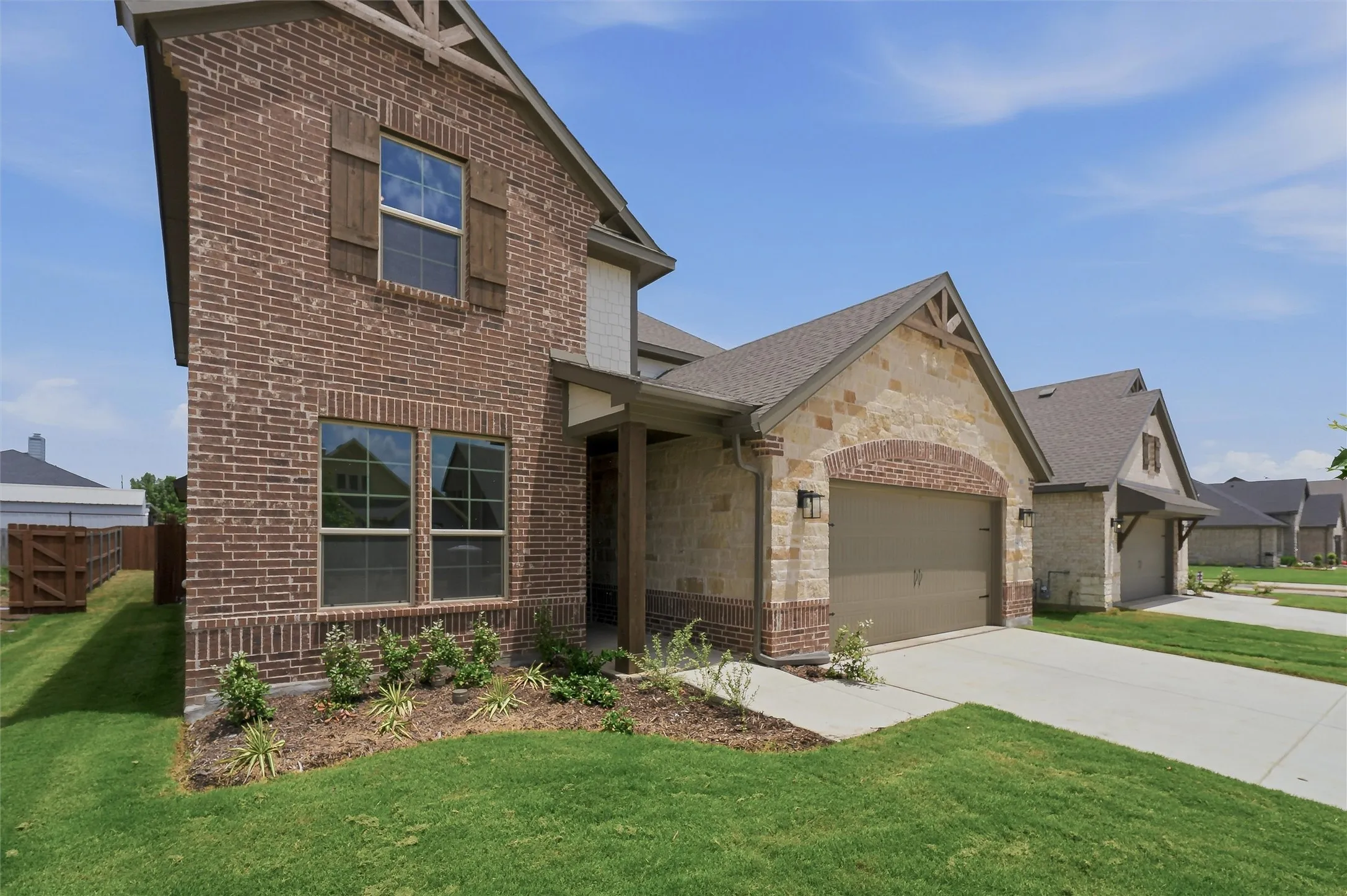 Two-story residence featuring a brick and stone facade, covered entry, and attached garage