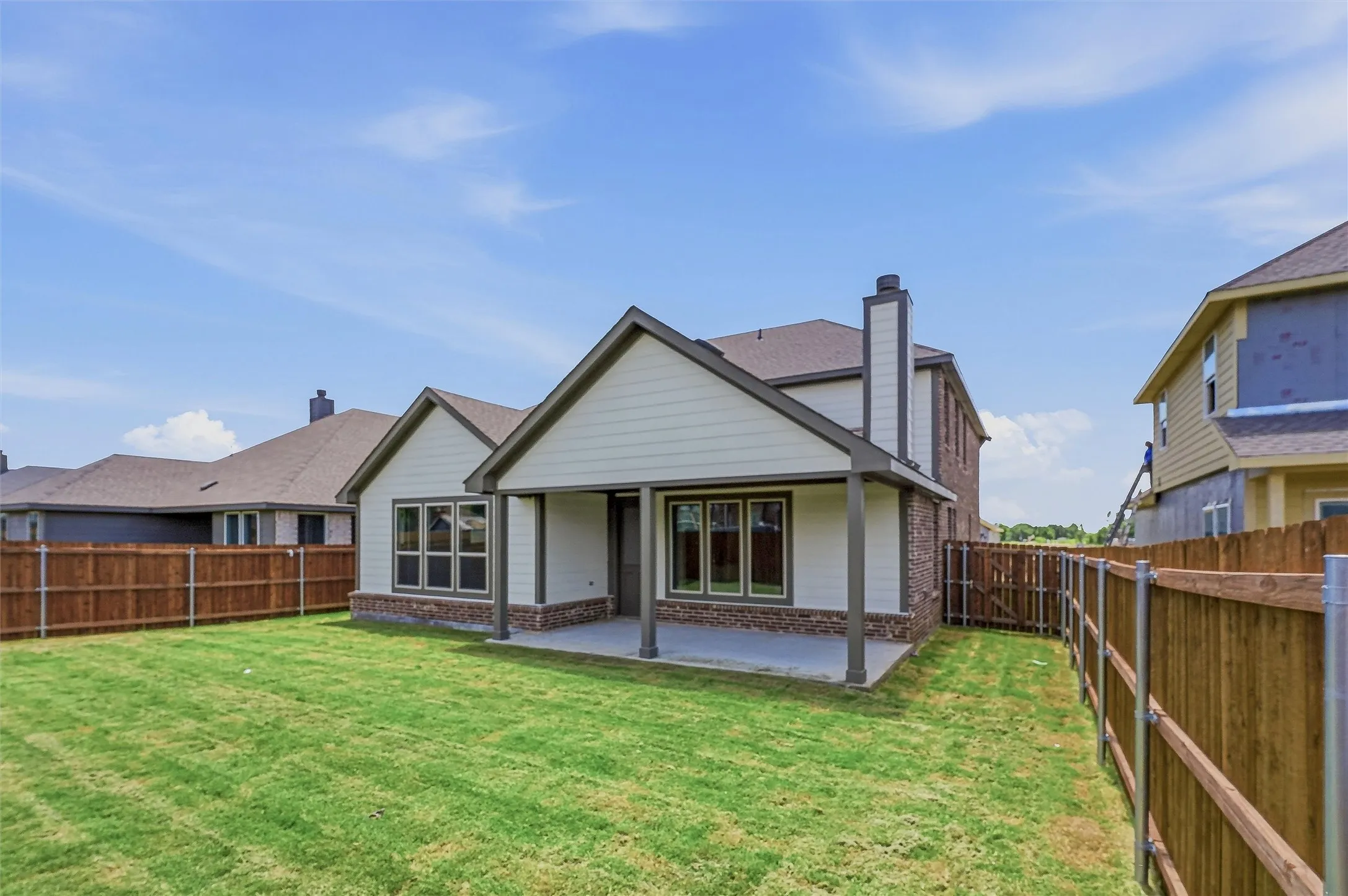 Expansive backyard featuring a covered patio, manicured lawn, and privacy fencing