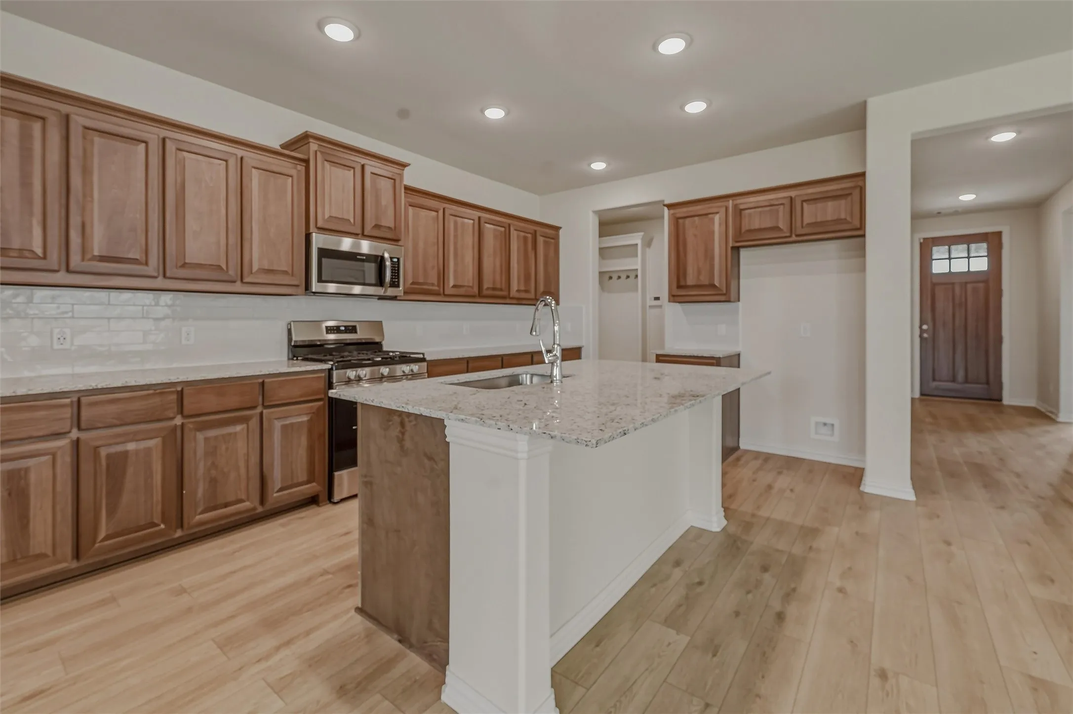 Open-concept kitchen featuring wood-finish flooring, recessed lighting, and a kitchen island with a stone countertop