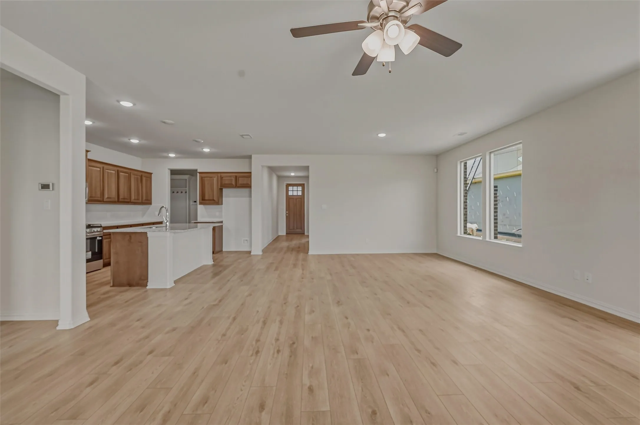 Open-concept living space featuring wood-finish flooring, recessed lighting, and a ceiling fan