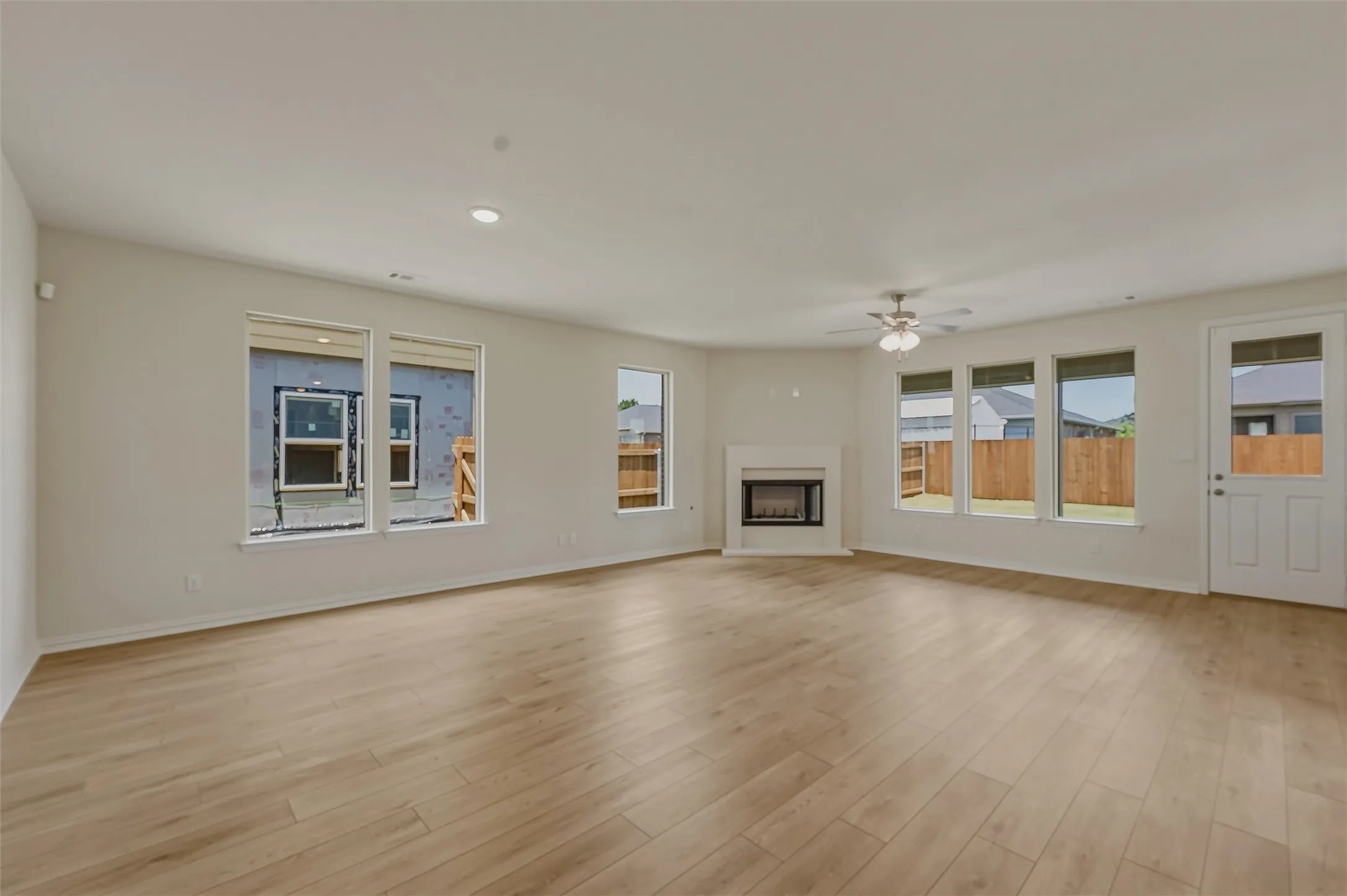 Spacious living area featuring wood-finish flooring, a contemporary fireplace, multiple windows, recessed lighting, and a ceiling fan