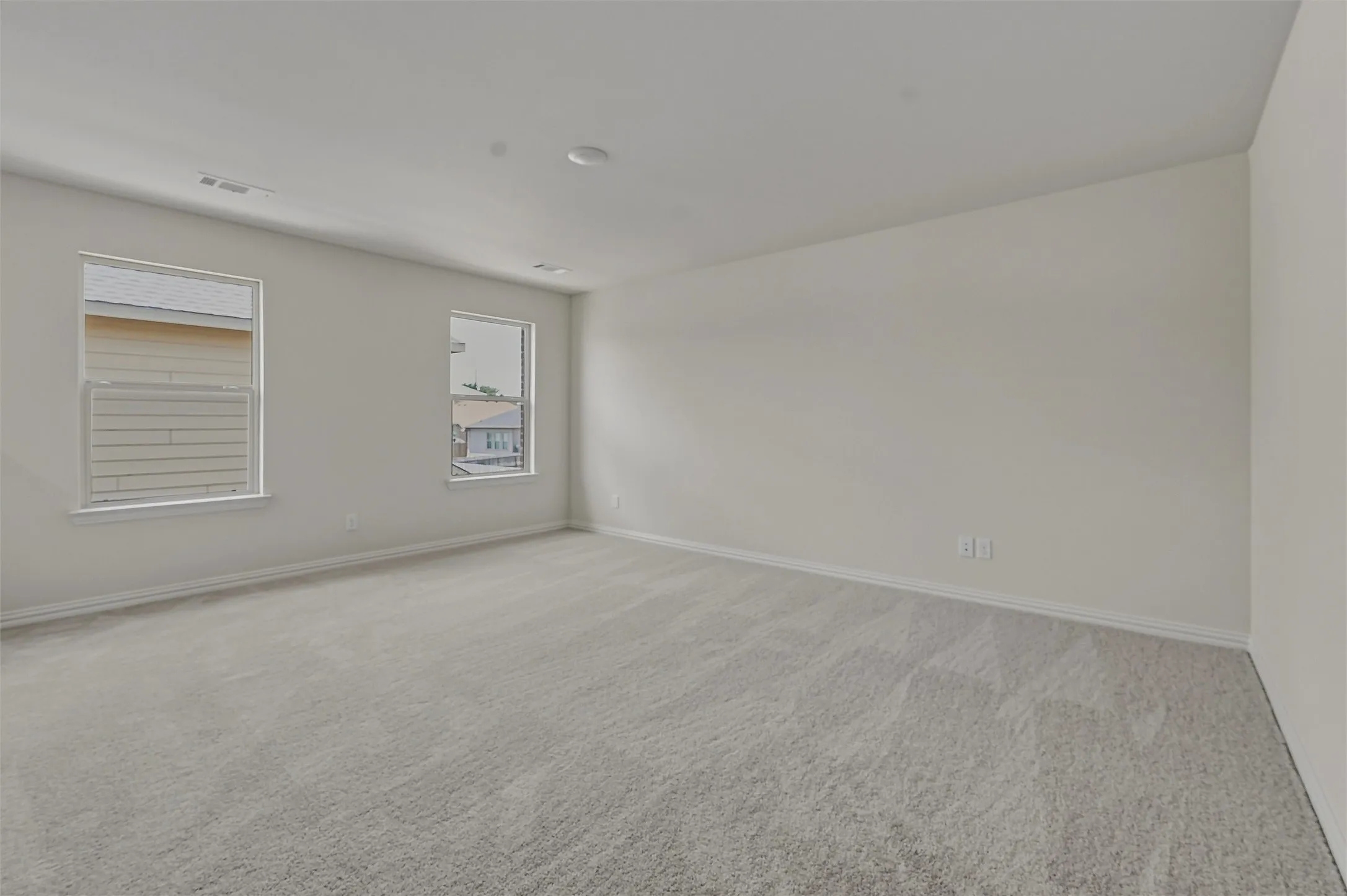 Spacious room featuring light gray carpeting and white painted walls