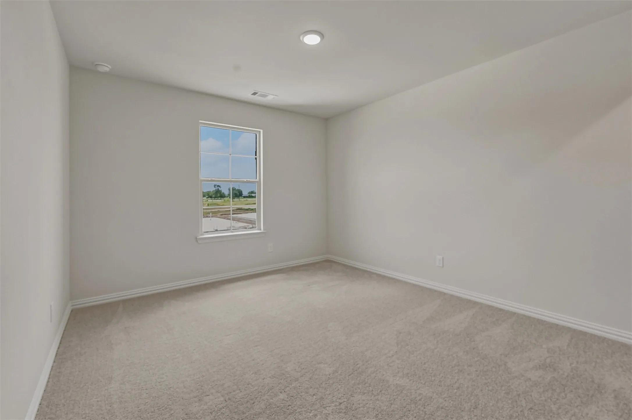 Carpeted room with a single window and recessed lighting