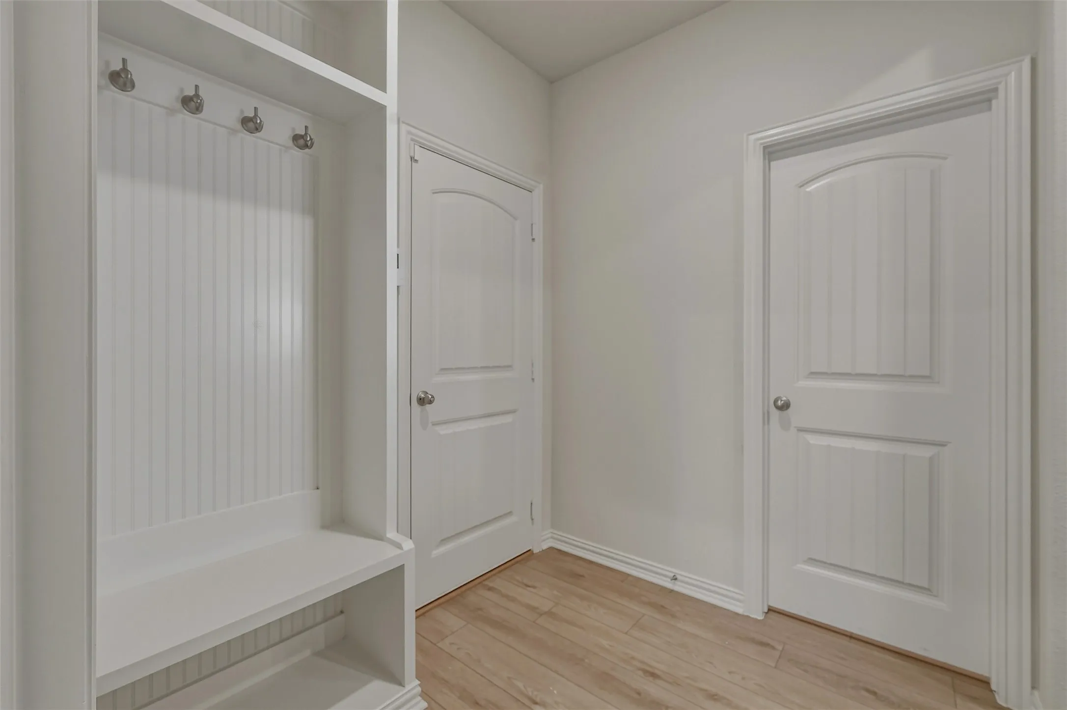 Built-in mudroom bench with beadboard backing and brushed nickel coat hooks