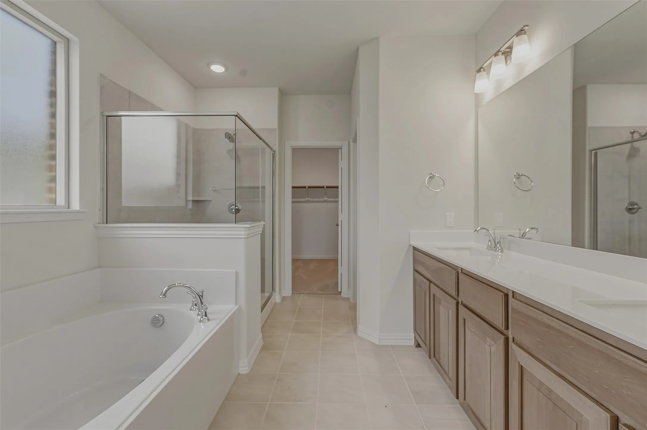 Bathroom featuring a dual vanity with light-colored countertops, an integrated soaking tub, a glass-enclosed shower, and tile flooring