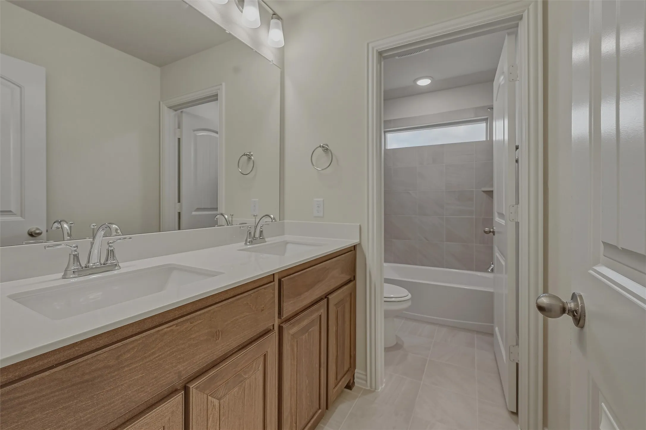 Double vanity with integrated sinks, wood-finish cabinetry, and a full-width mirror