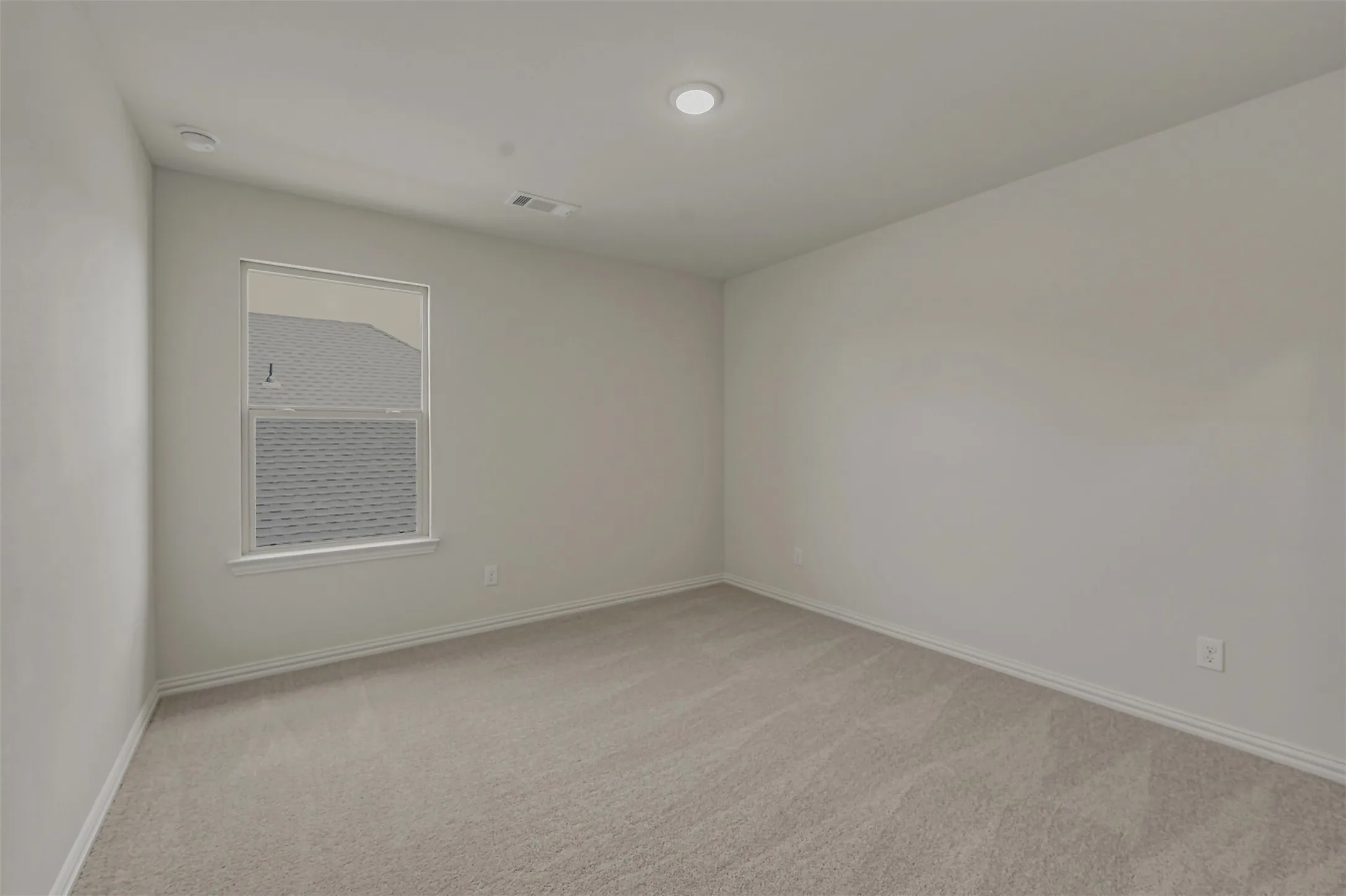 Carpeted interior room featuring a window with white trim, recessed ceiling lighting, and light-colored walls