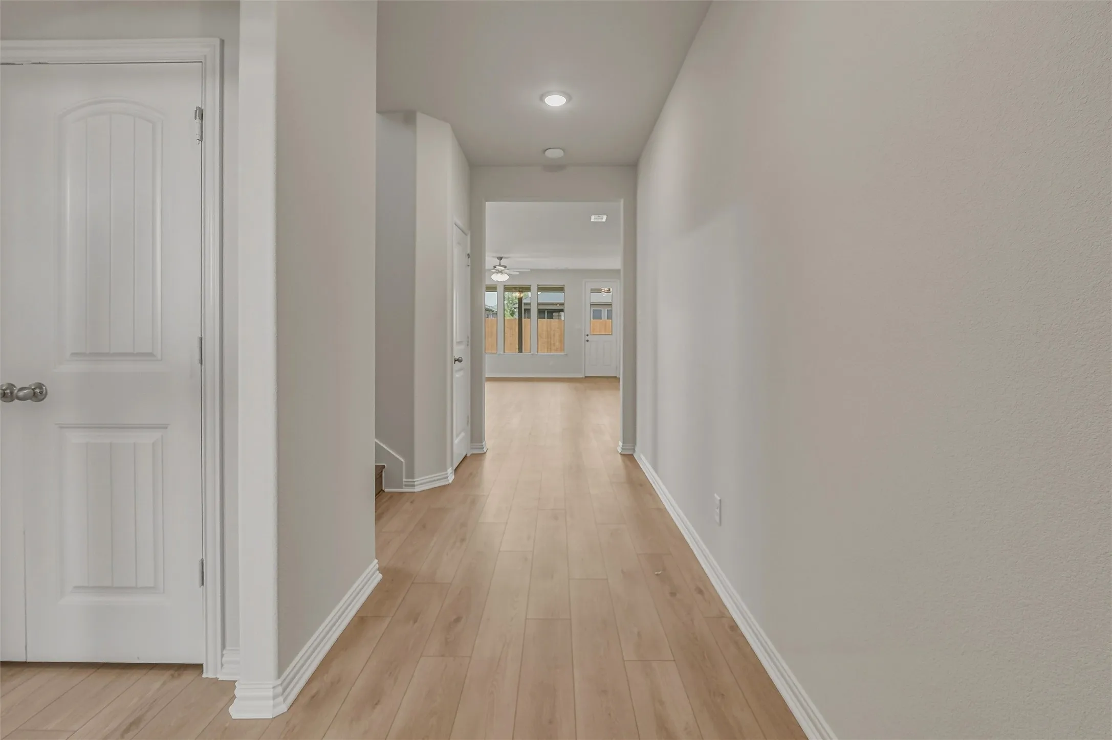 Hallway featuring wood-finish flooring, recessed lighting, neutral wall tones, and white baseboards