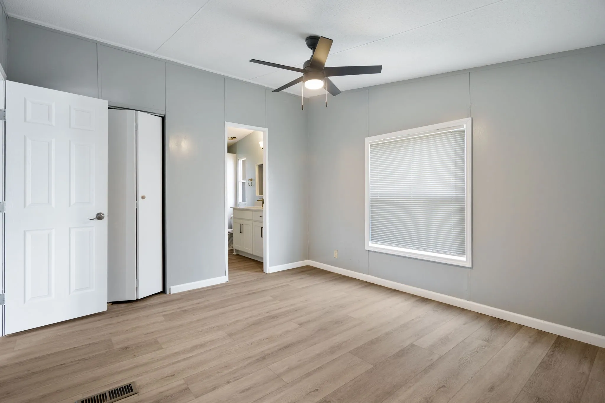 Interior room featuring gray wall panels and wood-finish flooring