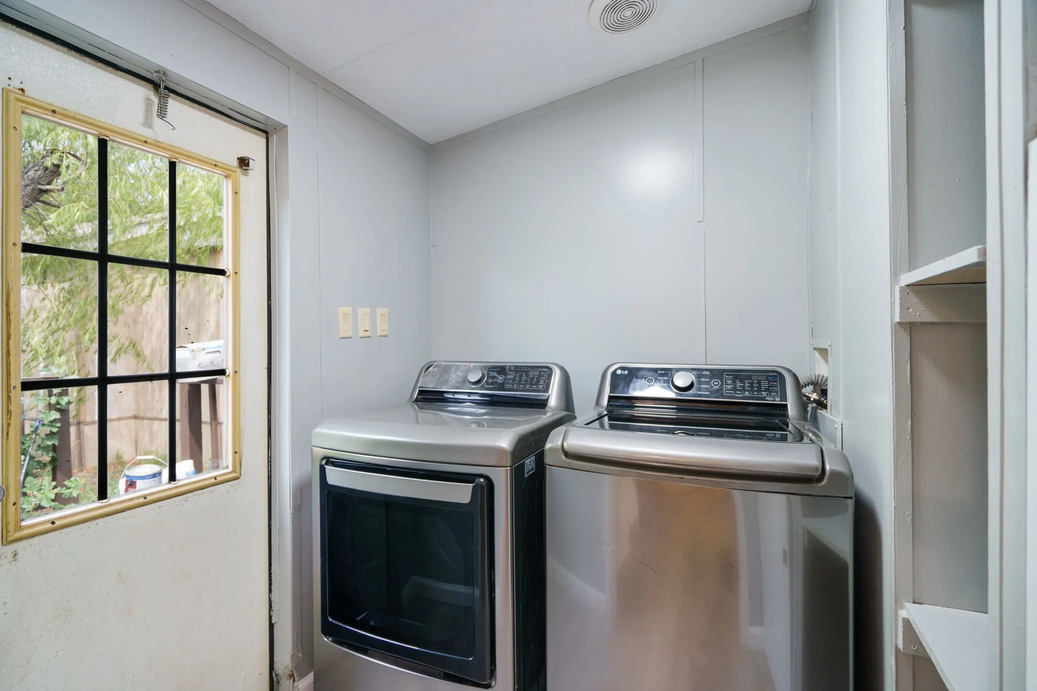 Utility space featuring light gray paneling and built-in shelving