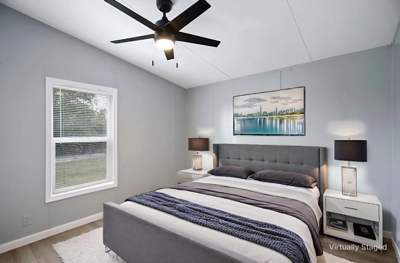 Bedroom featuring light gray walls, wood-finish flooring, a white window frame with blinds, a black ceiling fan with integrated lighting, and white baseboards
