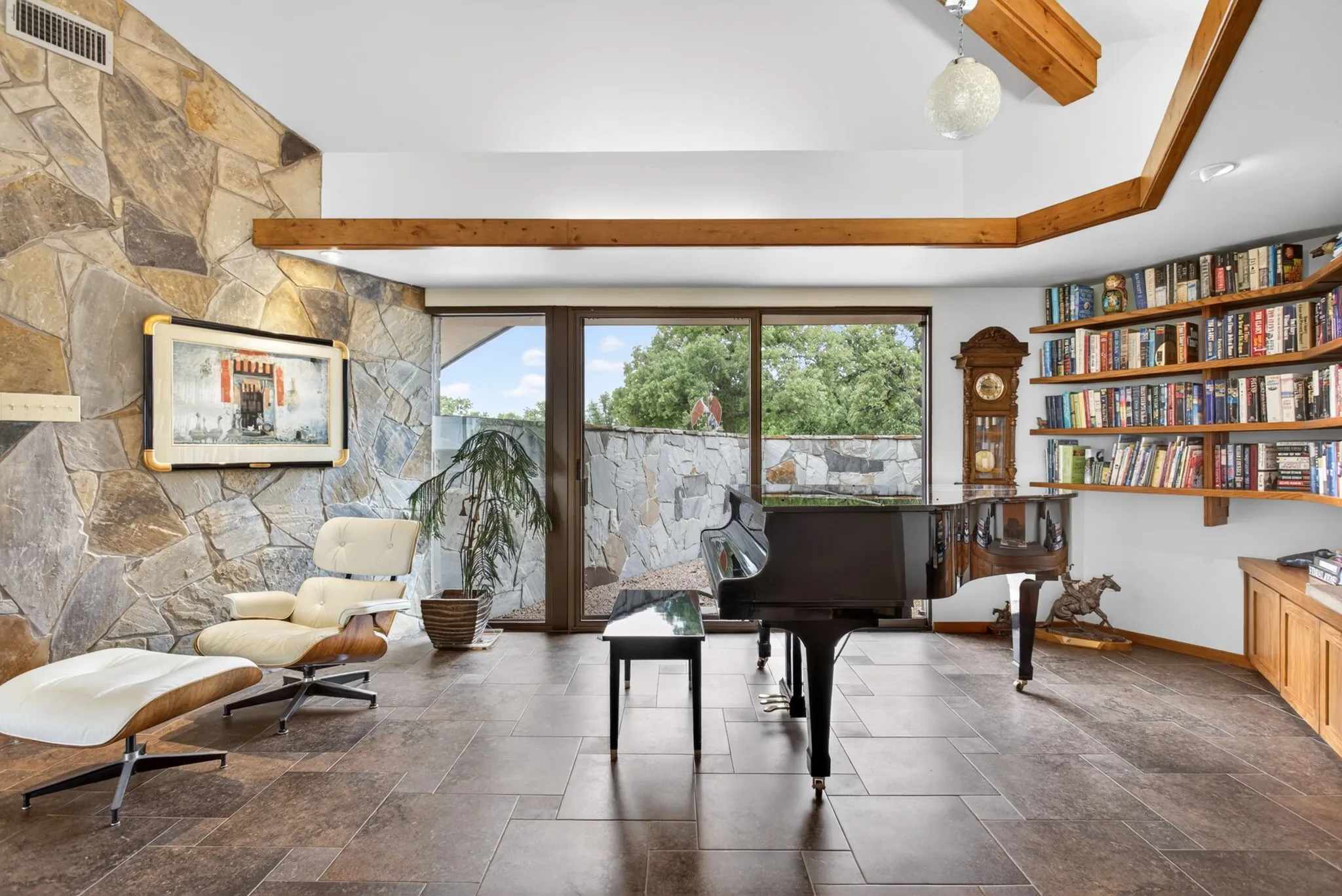 Expansive room featuring stone accent walls, large format tile flooring, exposed wood beams, and built-in shelving with integrated cabinetry