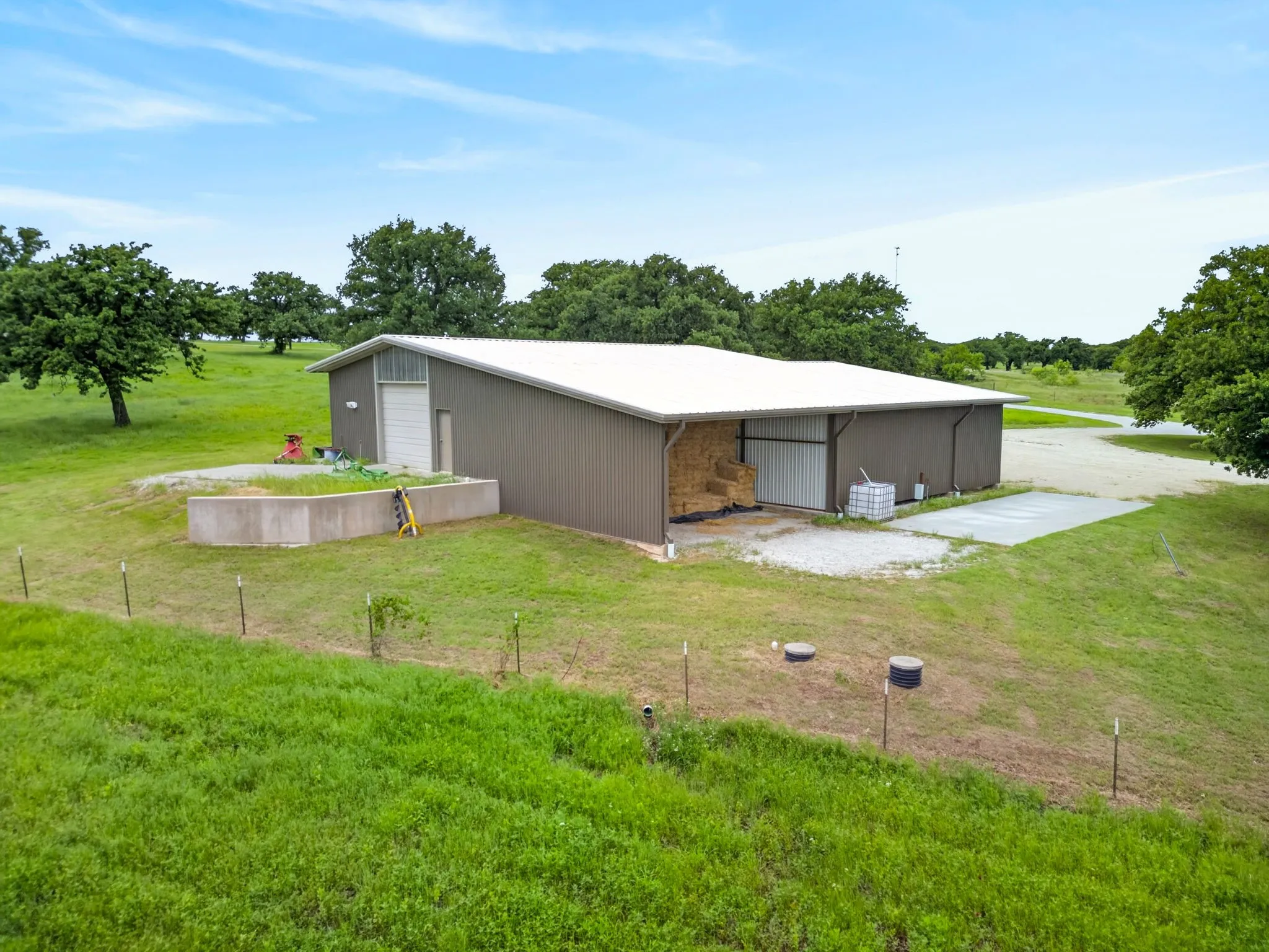 Expansive metal building featuring a white pitched roof, two large bay doors, and a covered open-air storage area