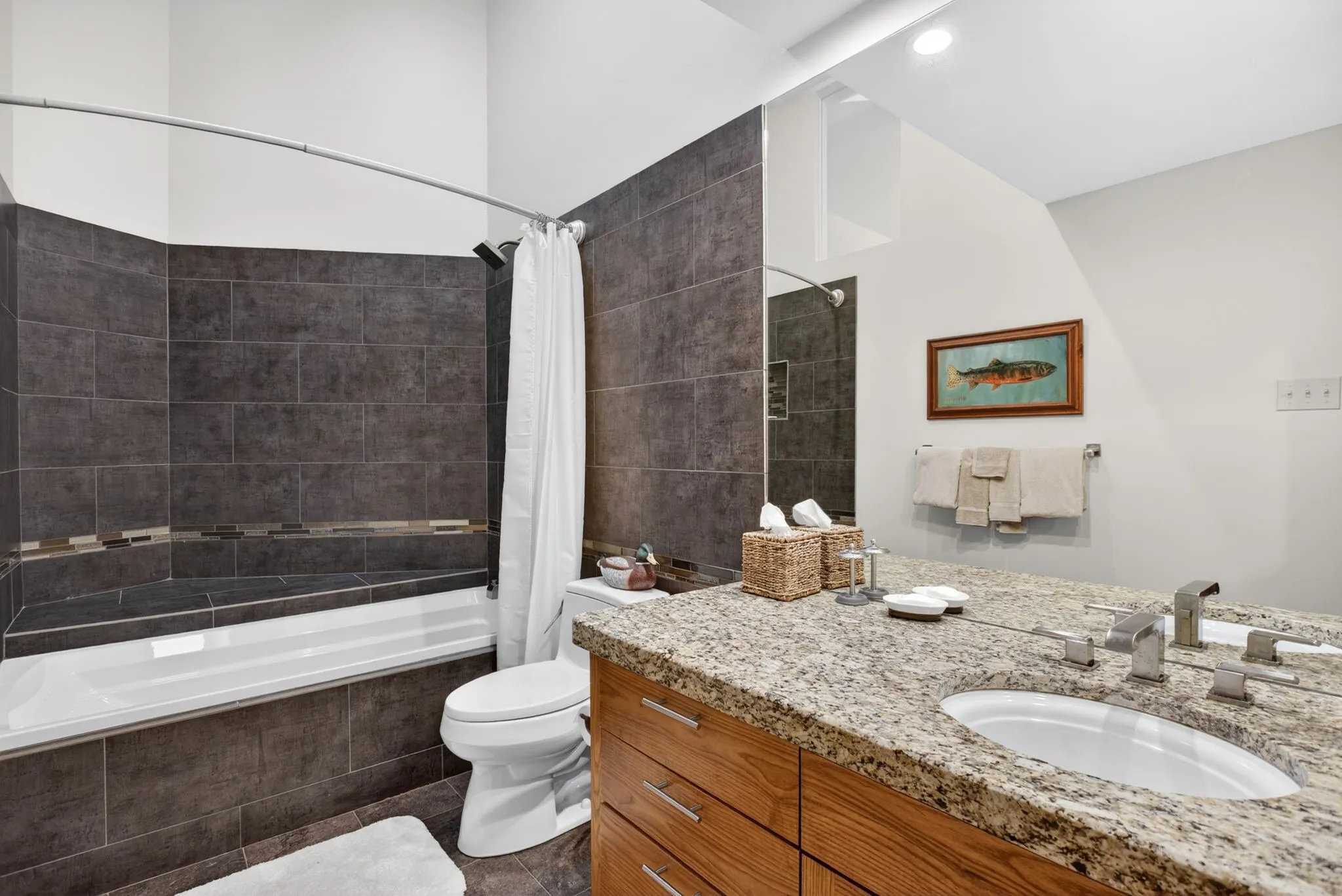 Bathroom featuring a tiled tub/shower combination, integrated storage bench, and a modern vanity with a single basin sink