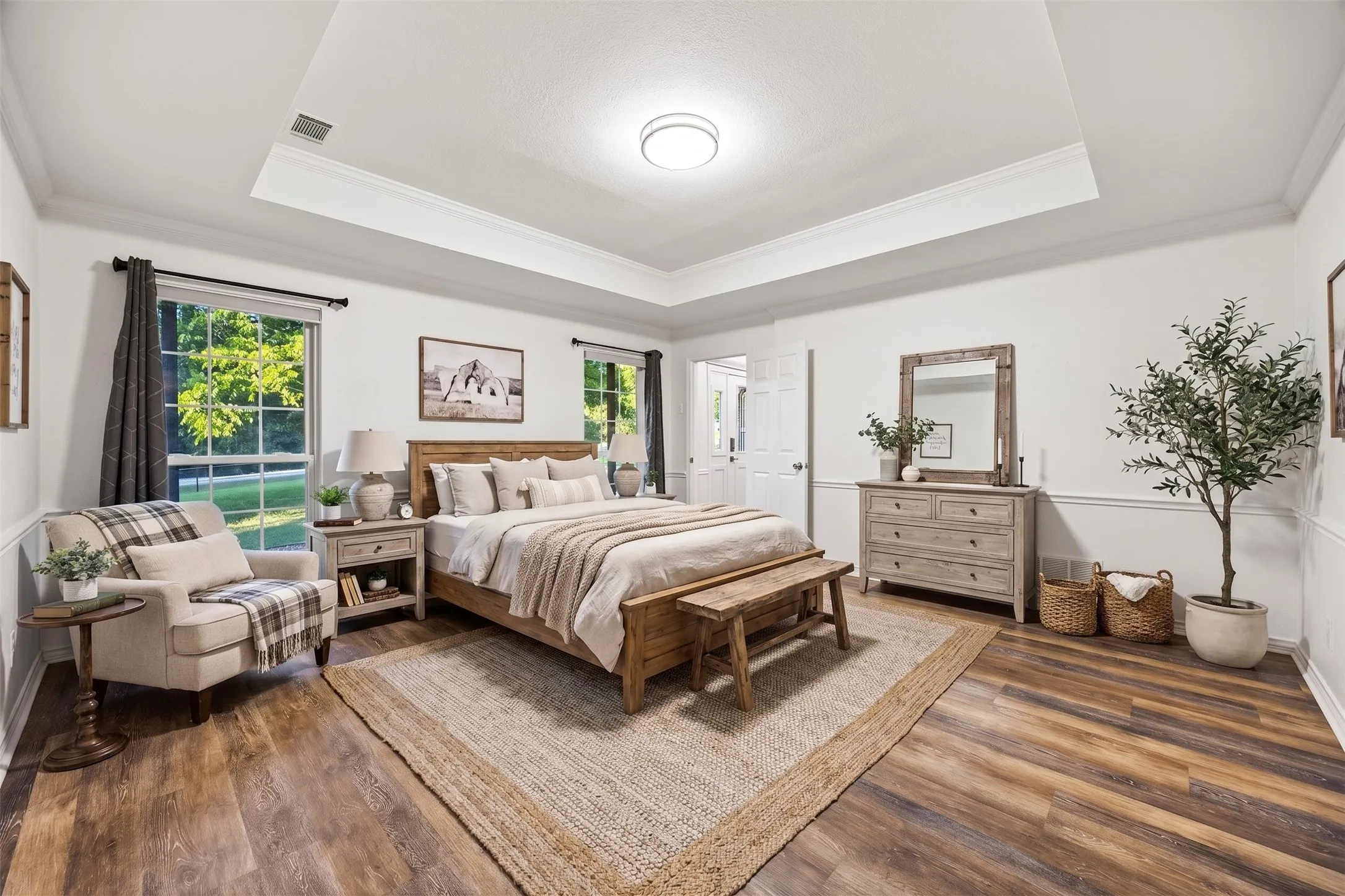 Spacious bedroom featuring wood-finish flooring, tray ceiling, and crown molding