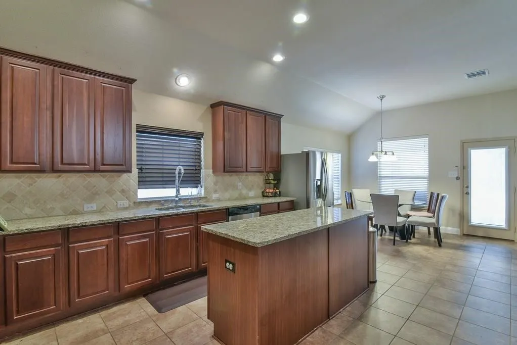 Kitchen featuring dark wood cabinetry, granite countertops, and a neutral tile backsplash