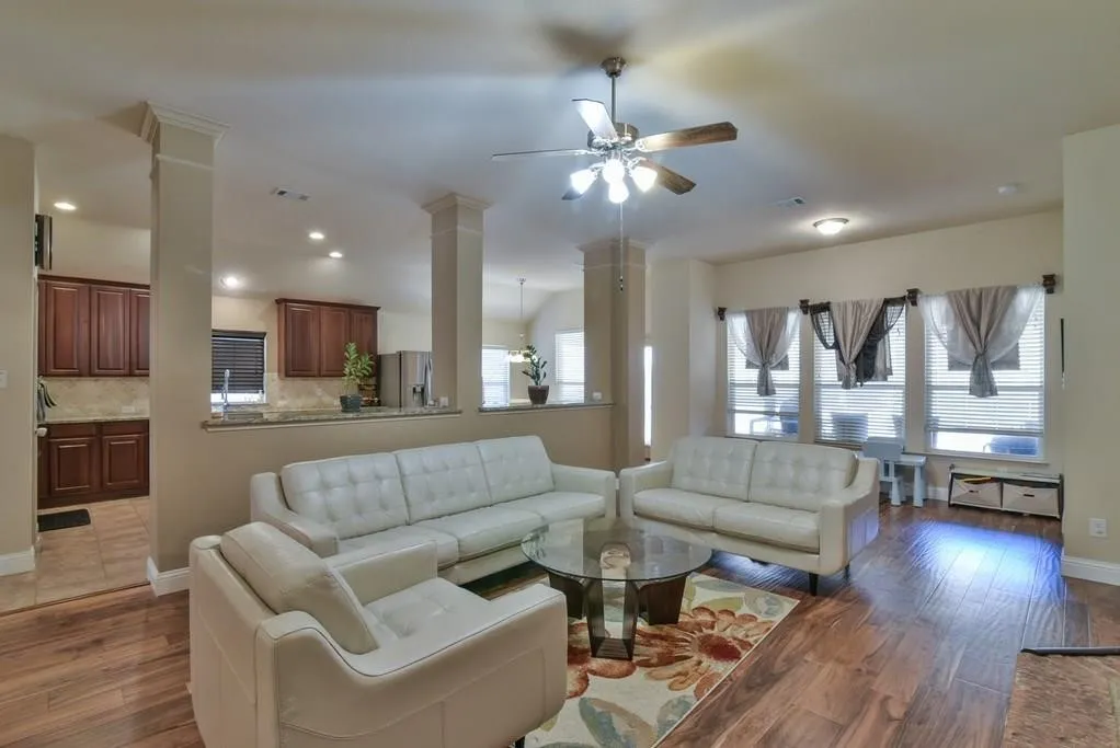 Expansive living area with wood-finish flooring, recessed lighting, and a ceiling fan