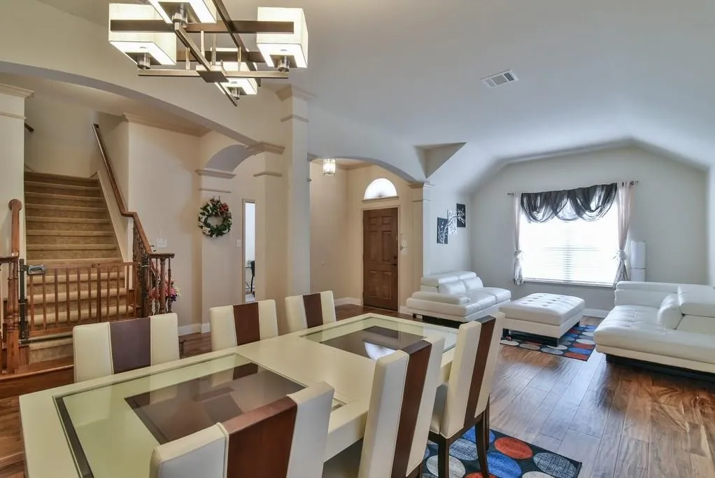 Spacious dining area with a modern chandelier and wood-finish flooring