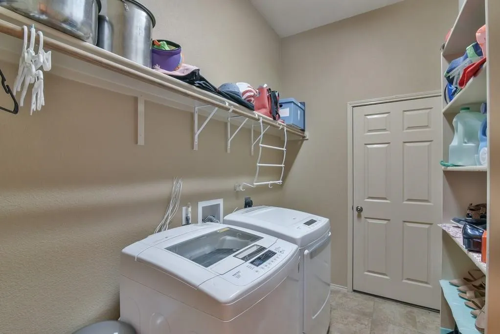 Dedicated laundry space featuring a practical overhead shelf, built-in storage shelving, and neutral wall paint