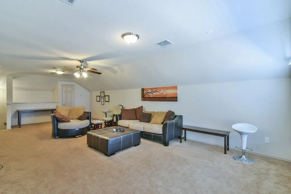Spacious carpeted room featuring a sloped ceiling, recessed lighting, and dual ceiling fans