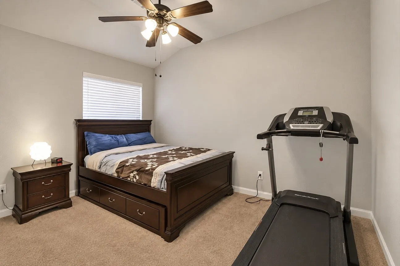 Bedroom featuring a vaulted ceiling with a ceiling fan, a window with horizontal blinds, and neutral carpeting