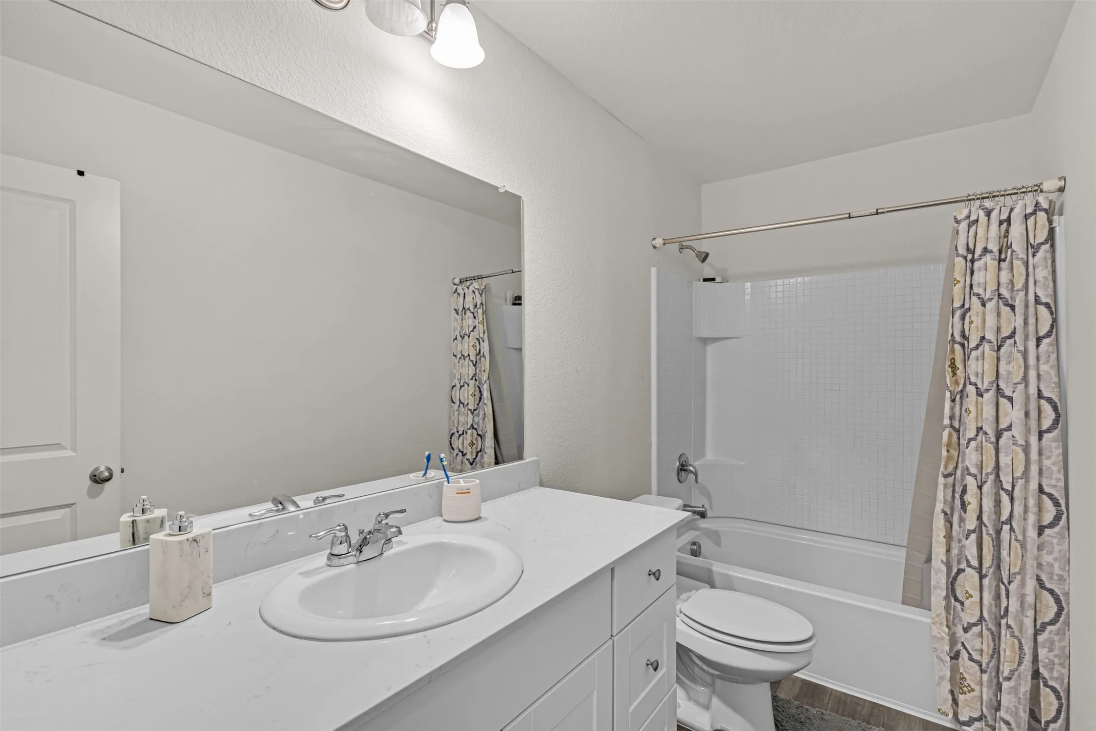Bathroom vanity featuring an integrated sink, polished chrome faucet, and expansive mirrored wall