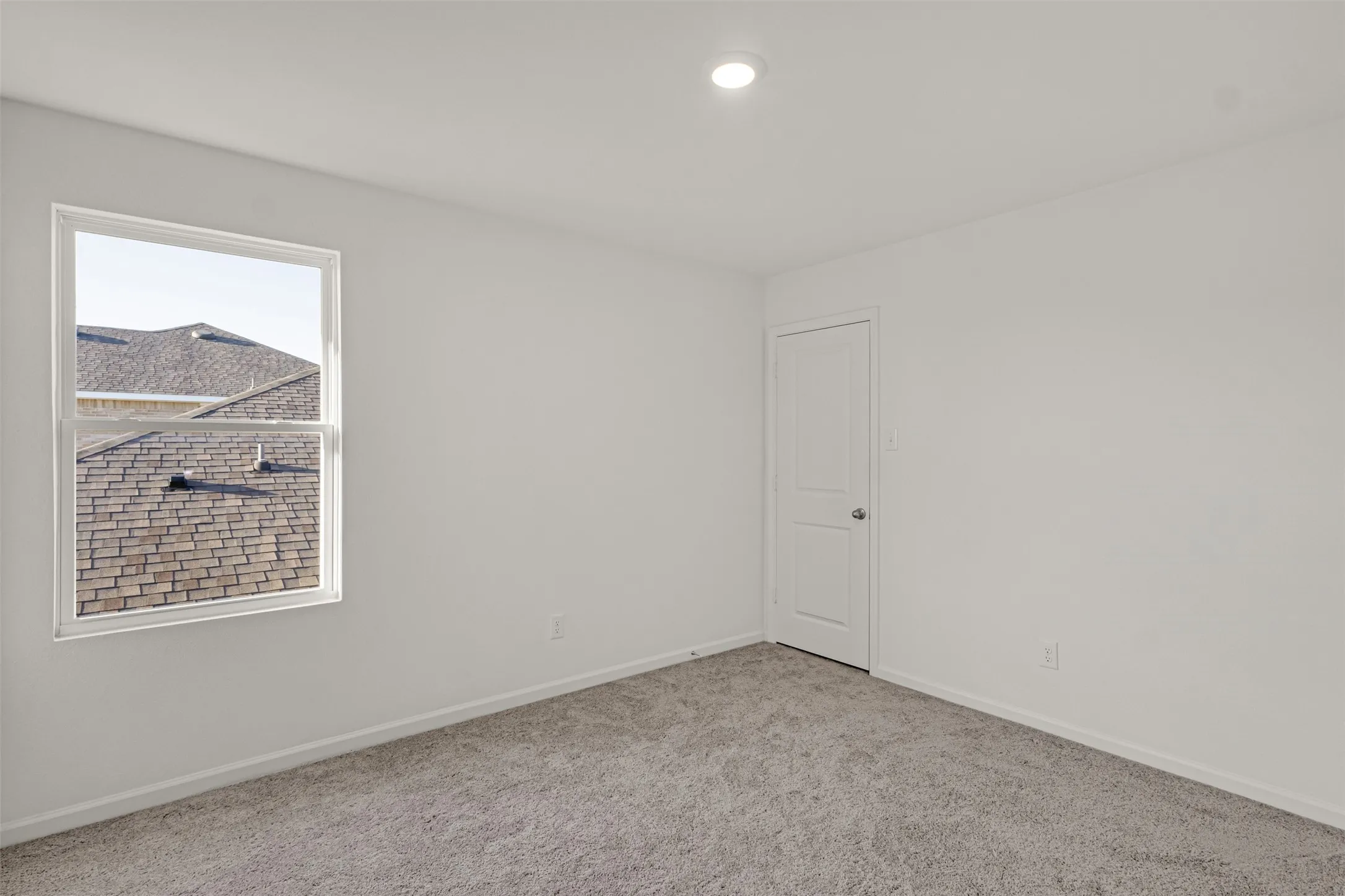 Carpeted room with a single window, recessed lighting, and a paneled door