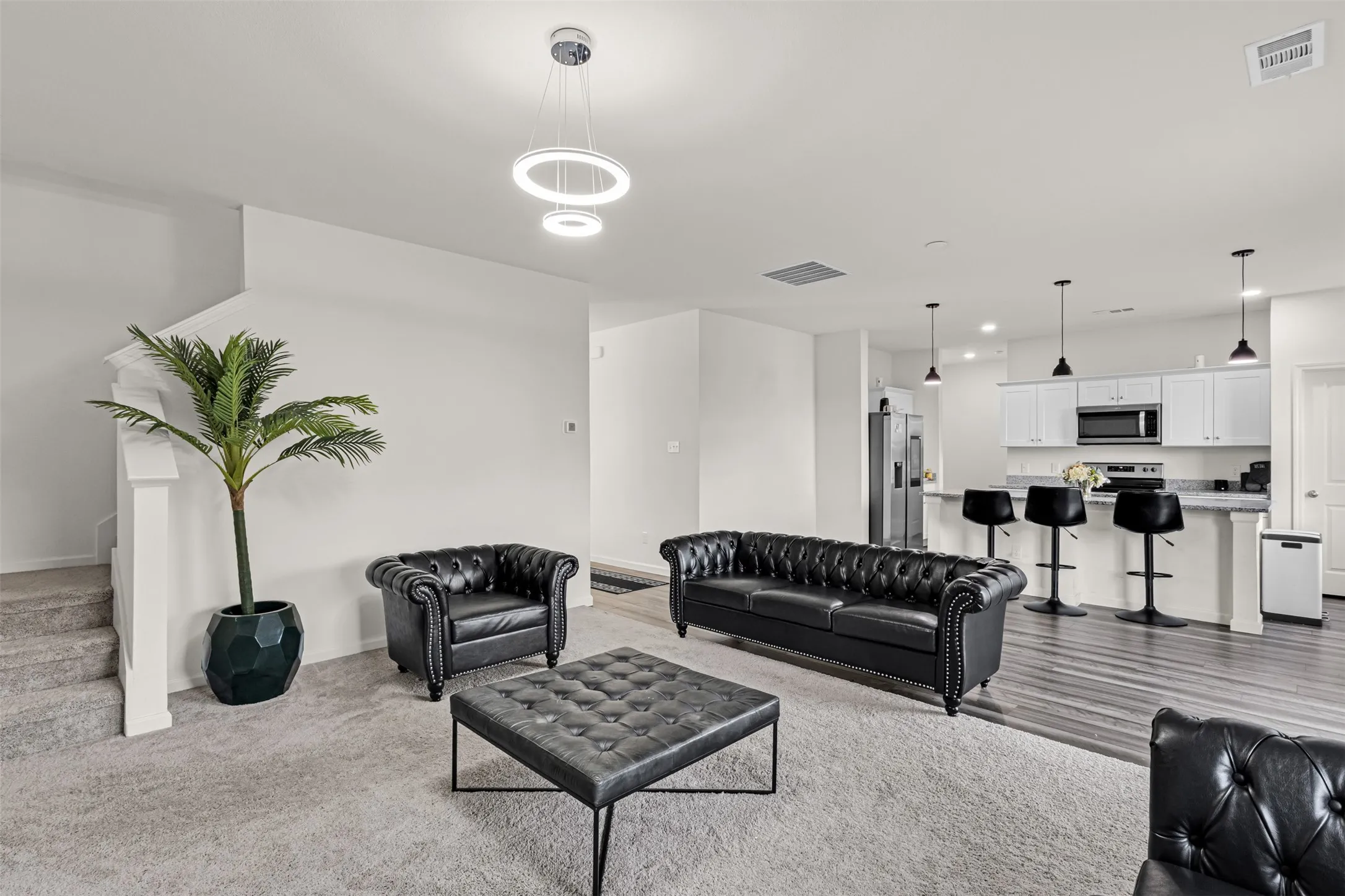 Open-concept living space featuring a modern kitchen with white cabinetry, light countertops, and pendant lighting