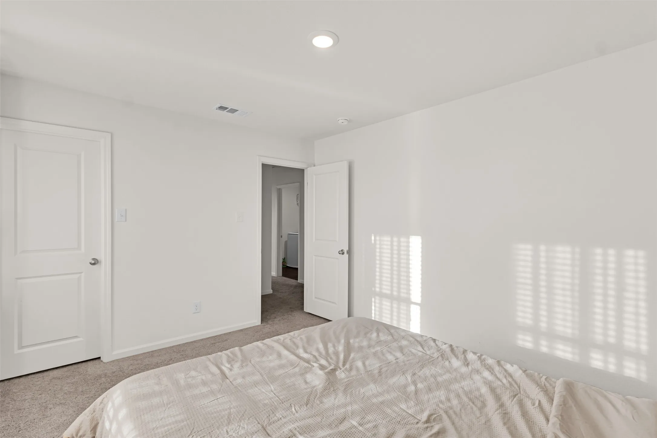 Bright interior room featuring neutral wall tones, recessed lighting, white trim, and light-toned carpet