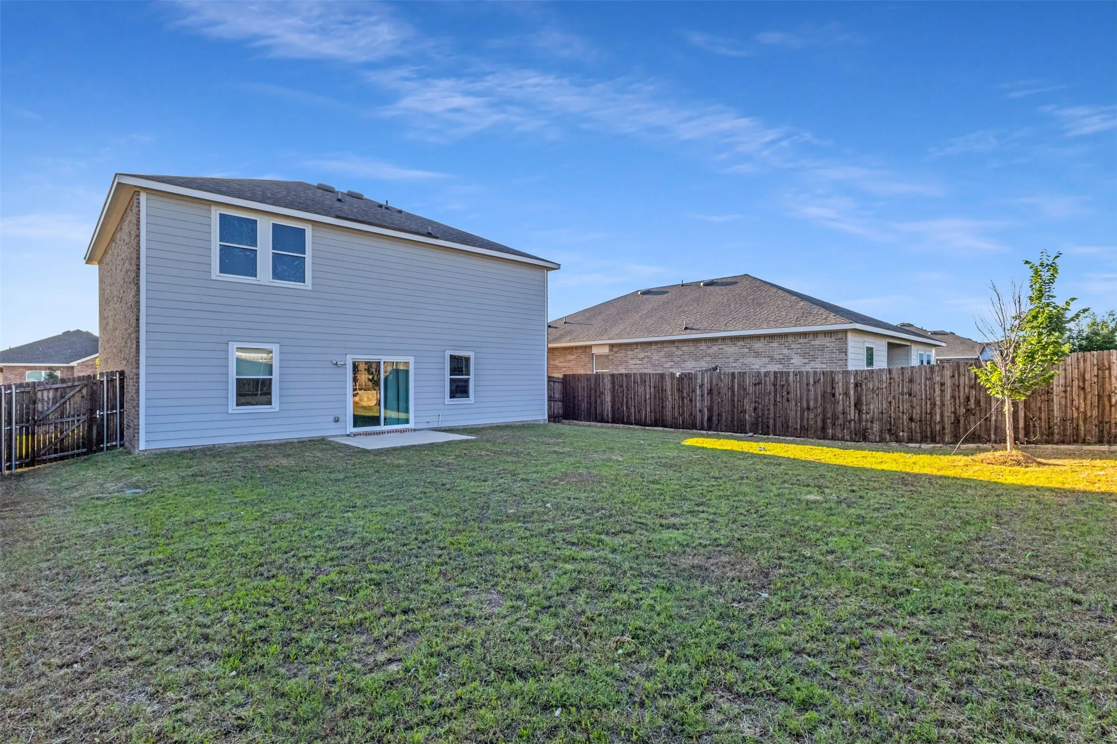 Expansive backyard with a manicured lawn, a concrete patio, and a privacy fence