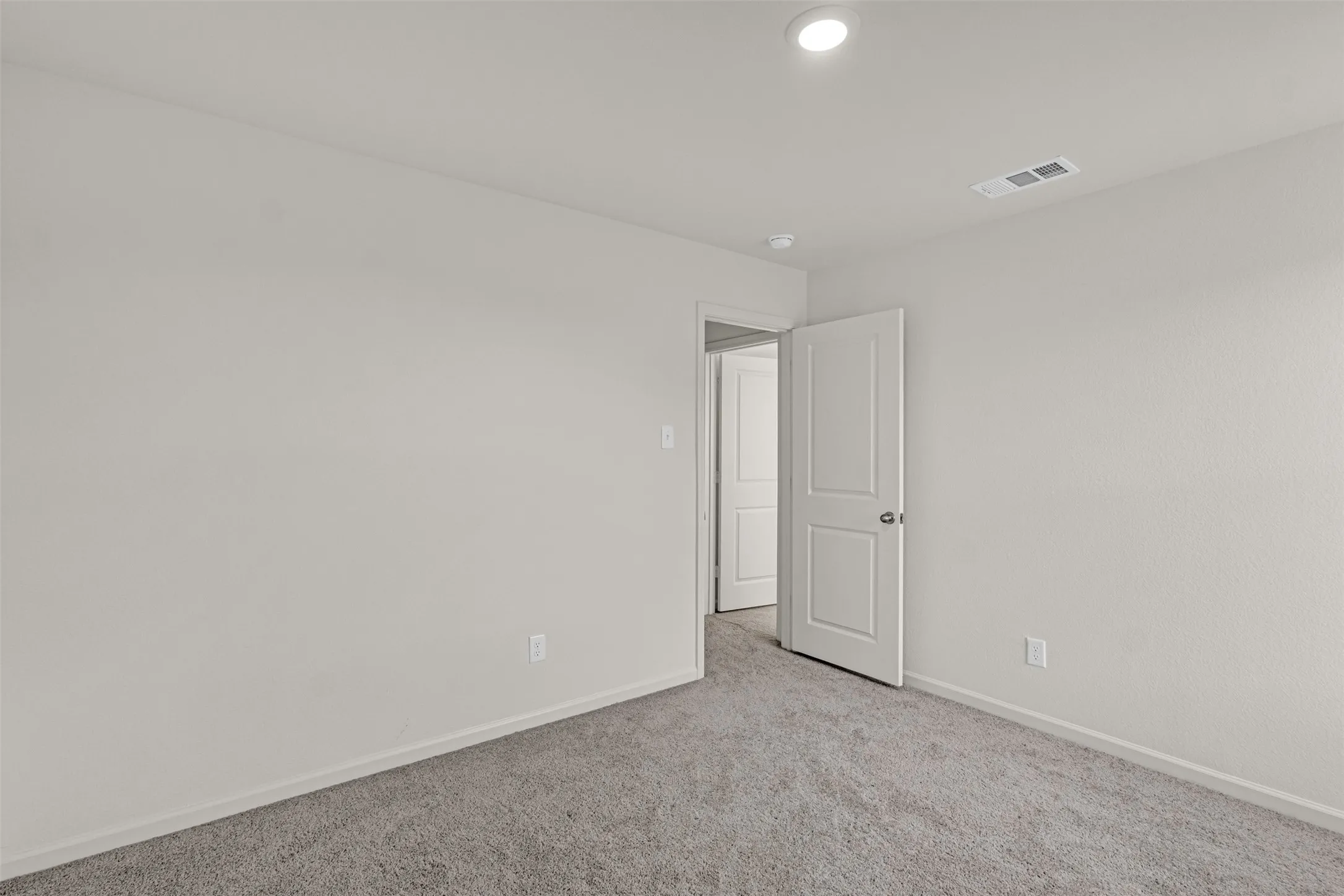 Neutral-toned walls complement plush grey carpeting